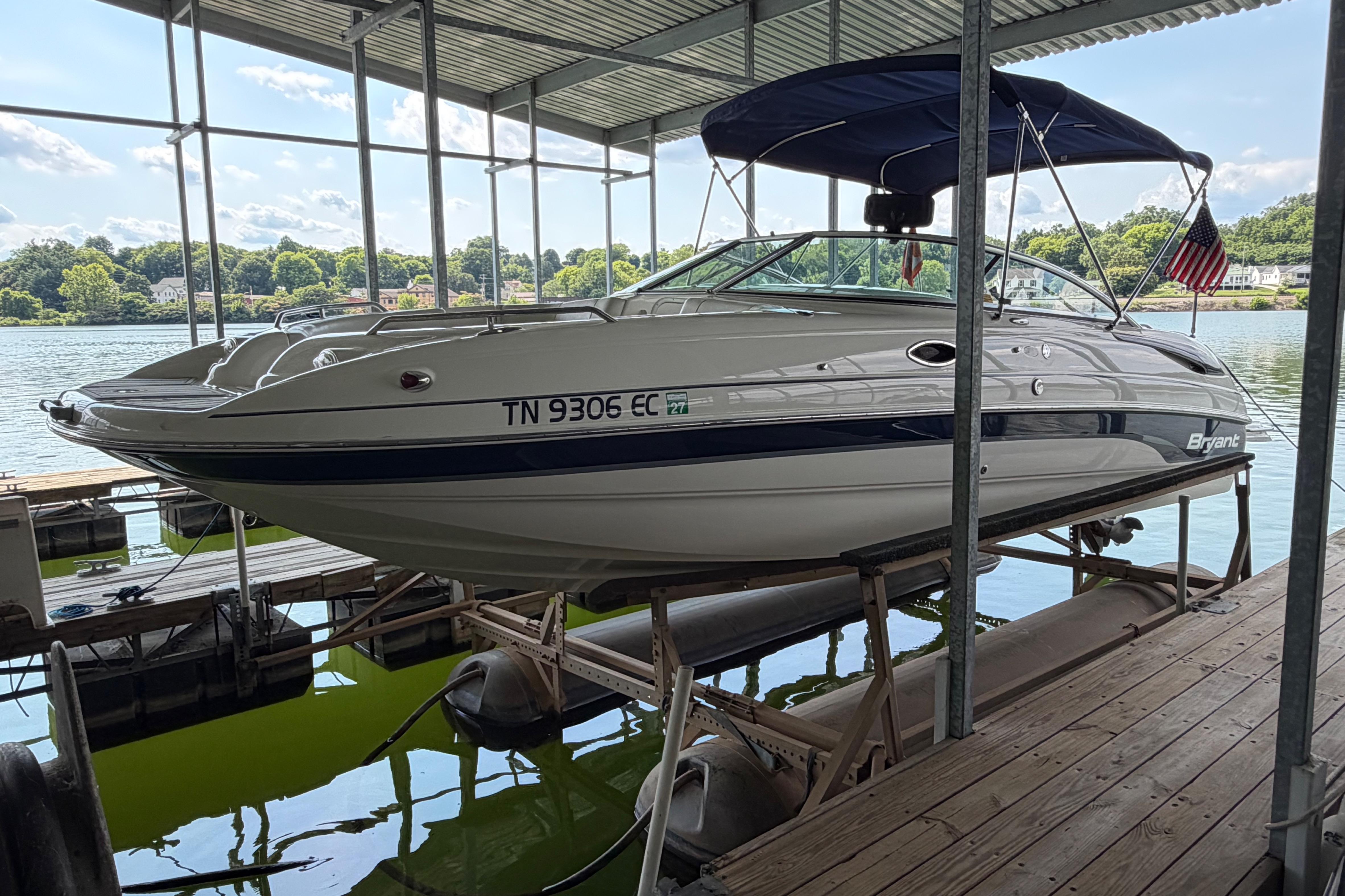 2010 Bryant 255 boat docked on a lift, with scenic lake background.
