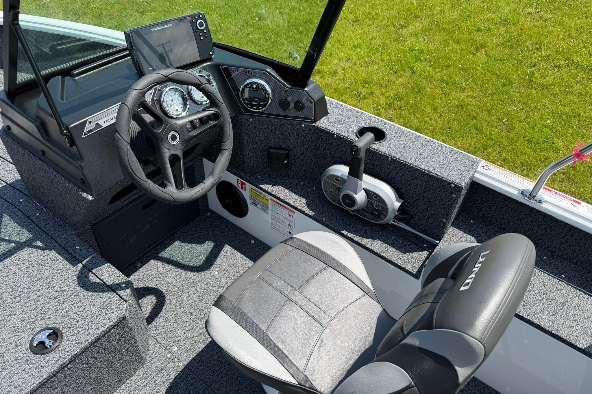 Interior of 2027 Lund 1675 Adventure Sport boat with steering wheel and control panel.