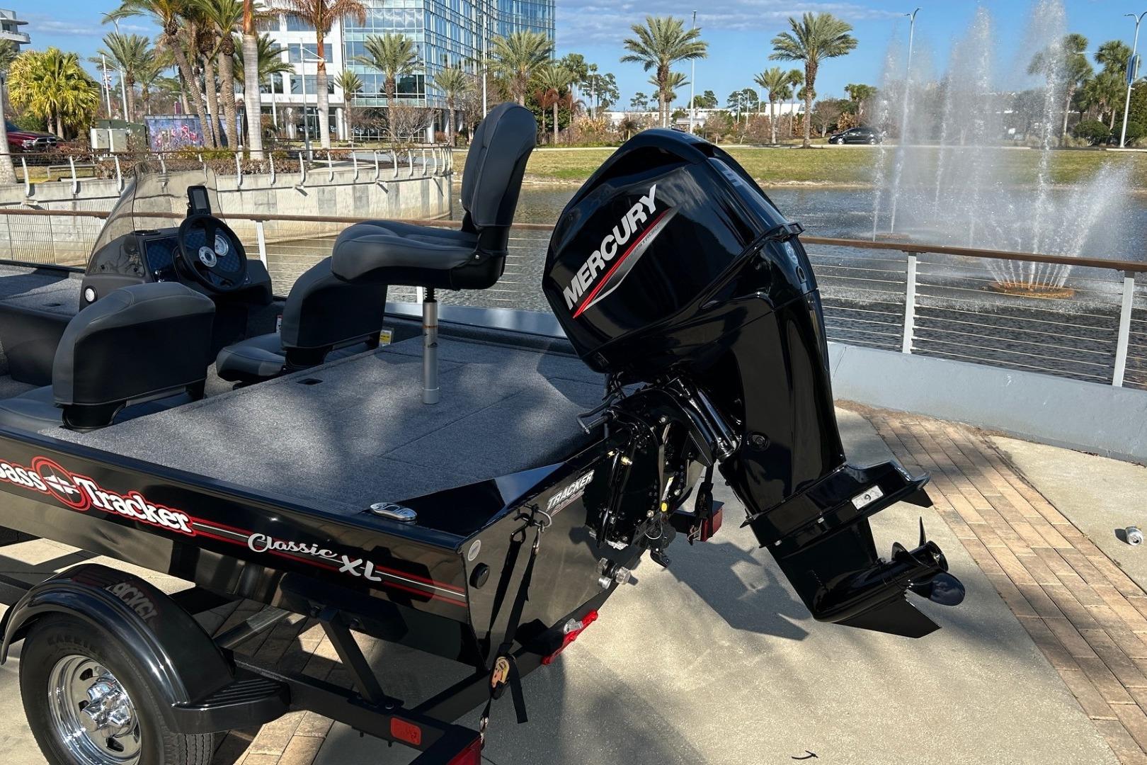 2026 Tracker Bass Tracker Classic XL boat with Mercury engine by a fountain.