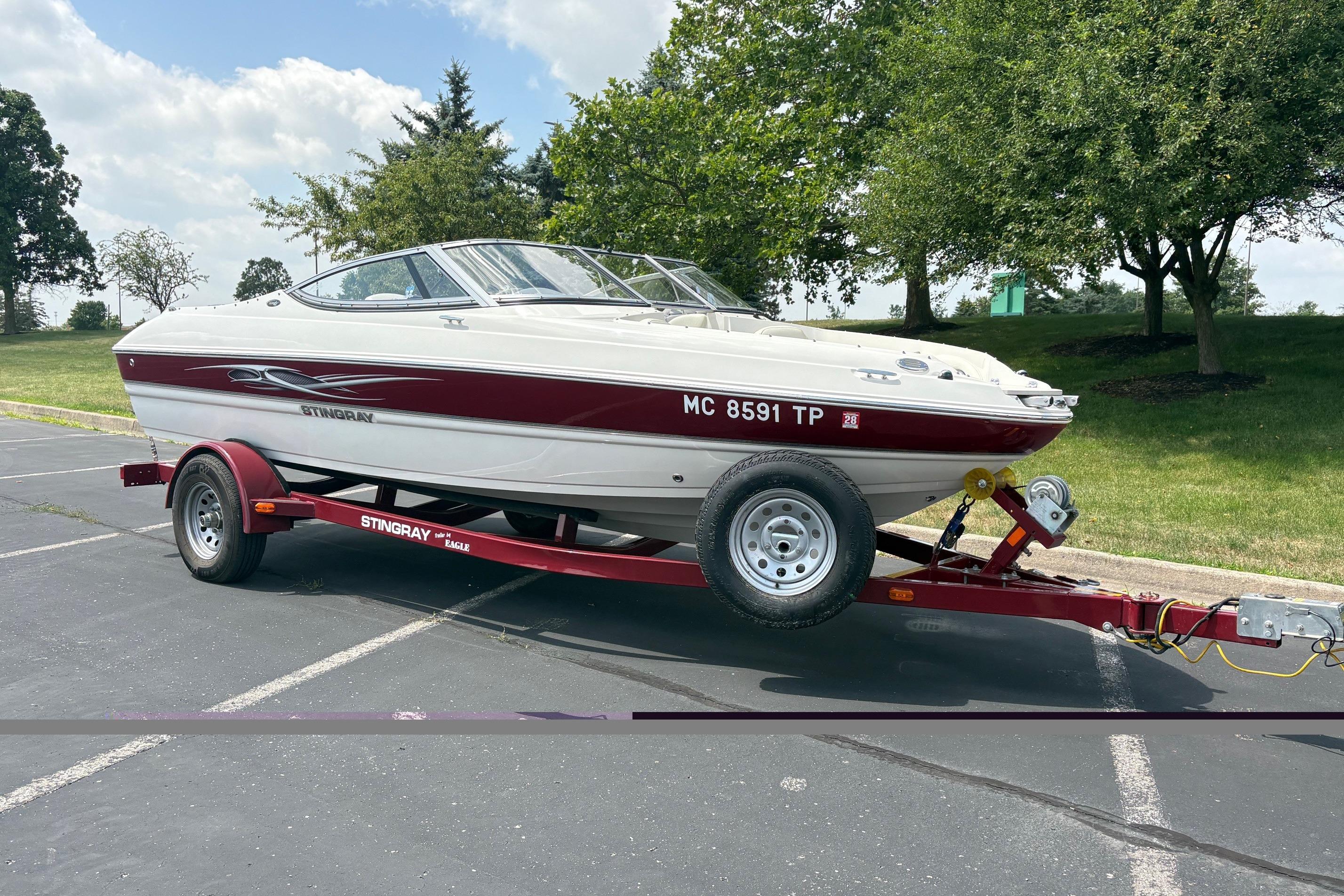 2013 Stingray 198 LX boat on trailer, parked outdoors with trees in the background.