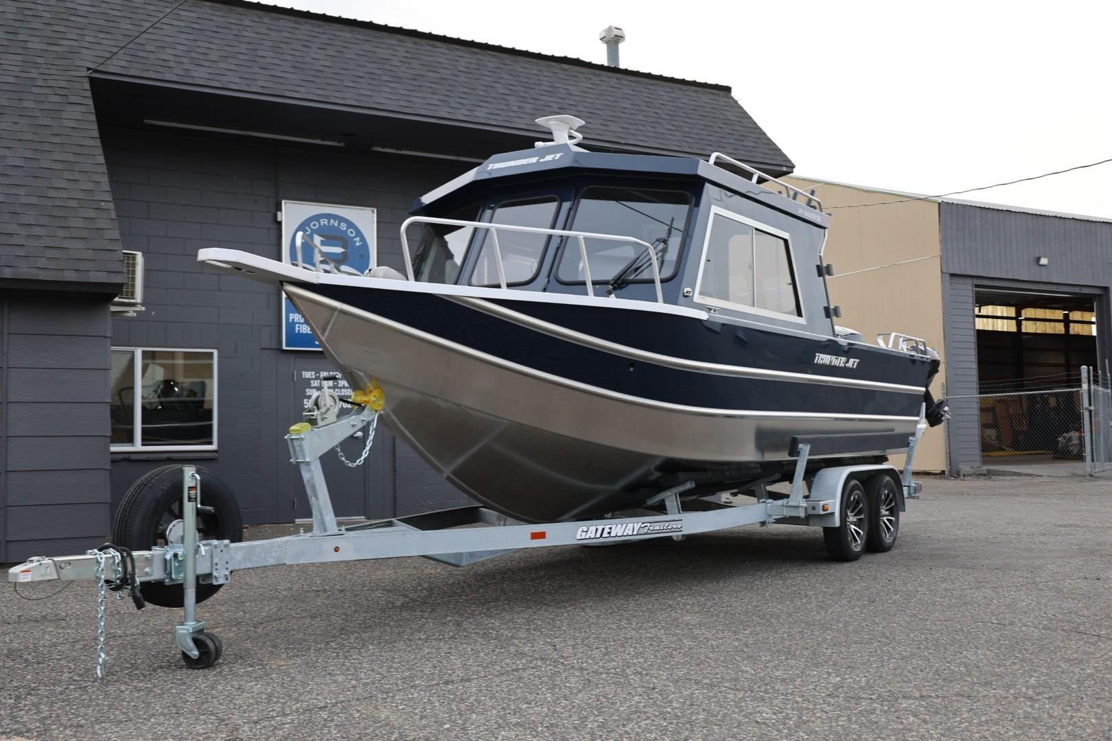 2026 Thunder Jet 24 Alexis Pro boat on trailer outside industrial building.