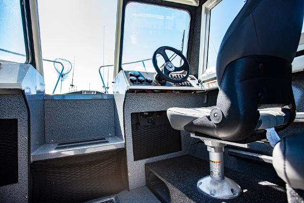 Interior cockpit of 2023 Spartan 220 Maximus Pro boat with steering wheel and captain's chair.