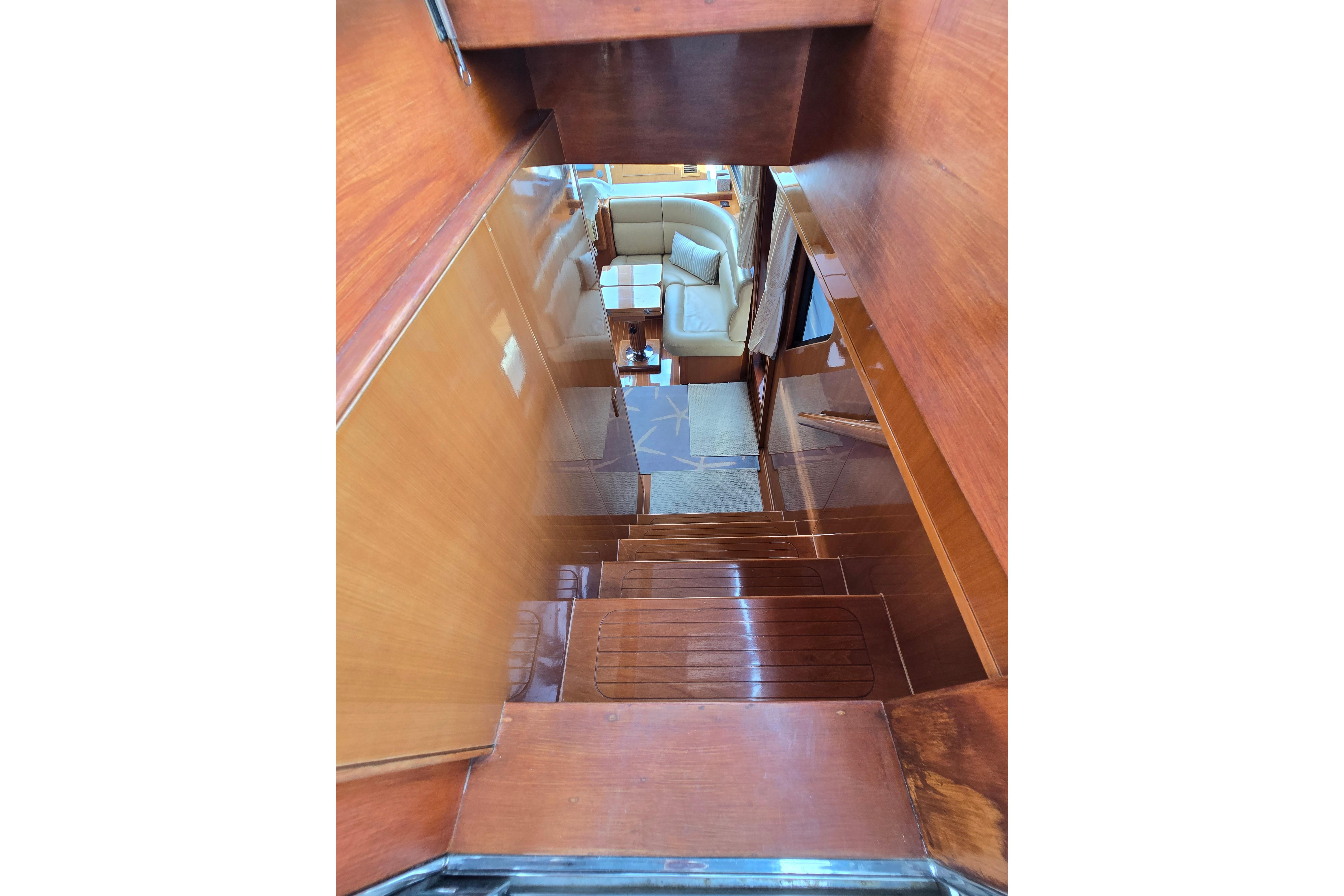 Interior view of 2004 Grand Harbour 58 yacht, featuring wooden stairs and a cozy seating area.