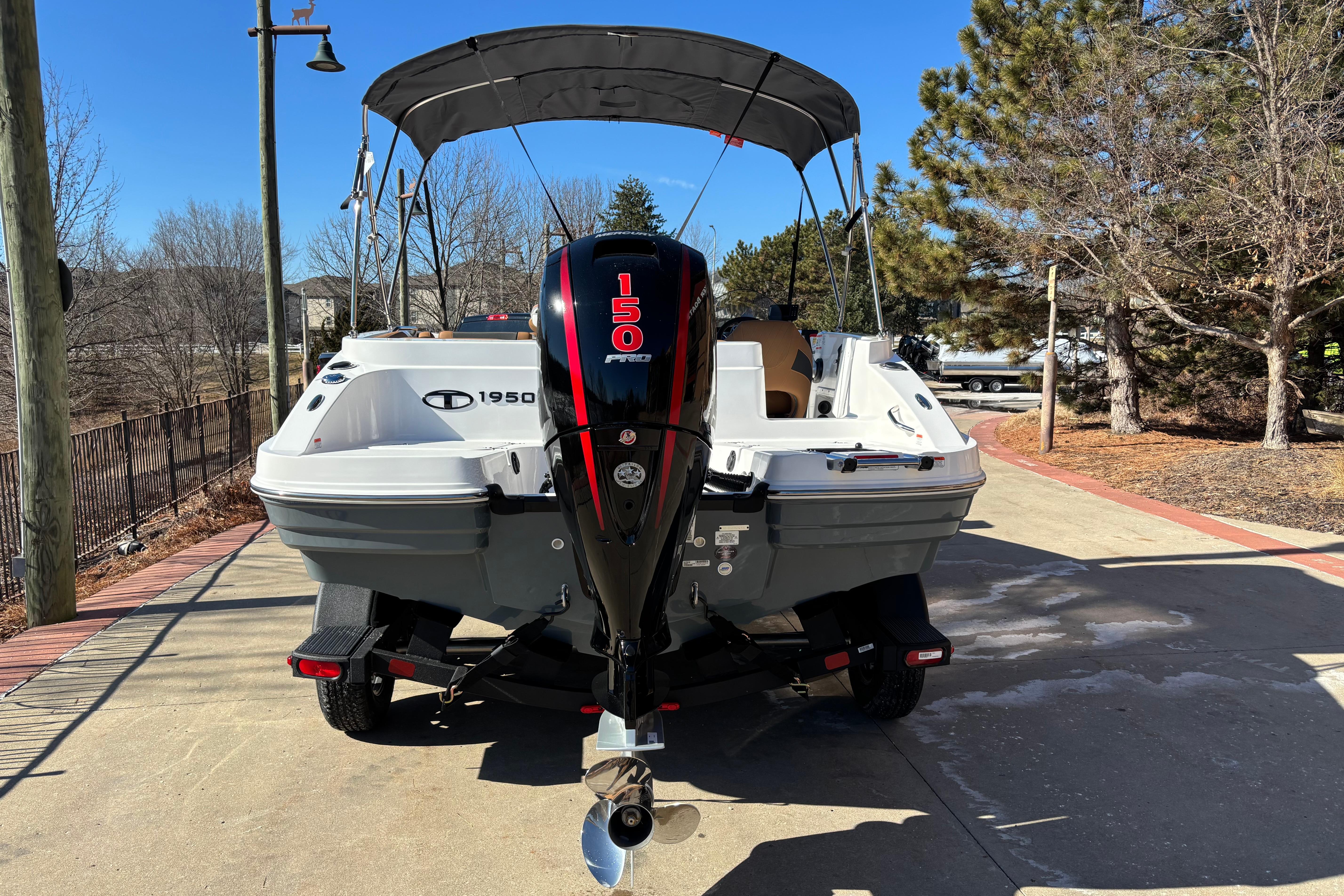 2026 Tahoe 1950 boat with 150 HP engine, parked on a sunny driveway.