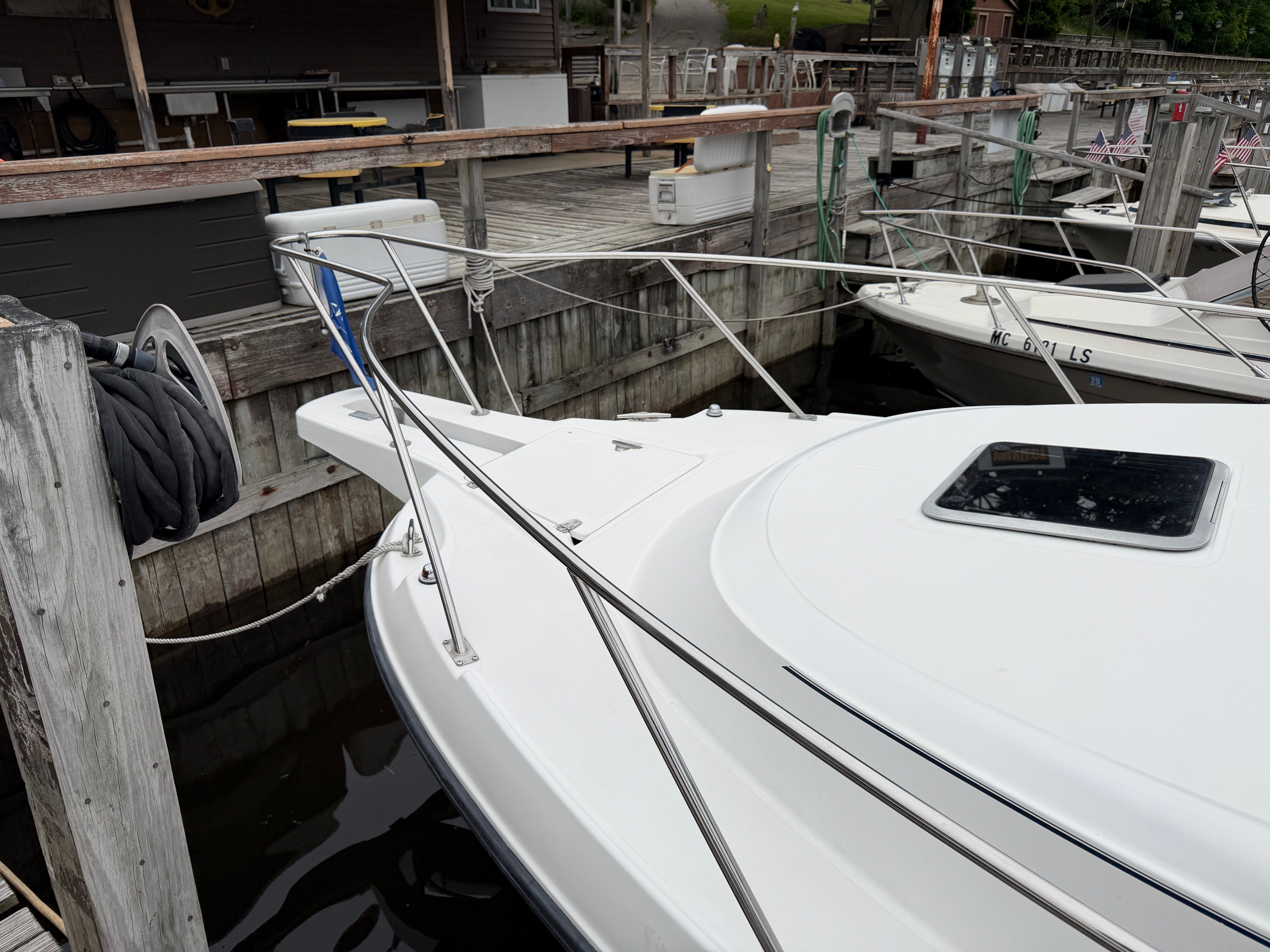A 2001 Boston Whaler 26 Conquest docked at a wooden pier.
