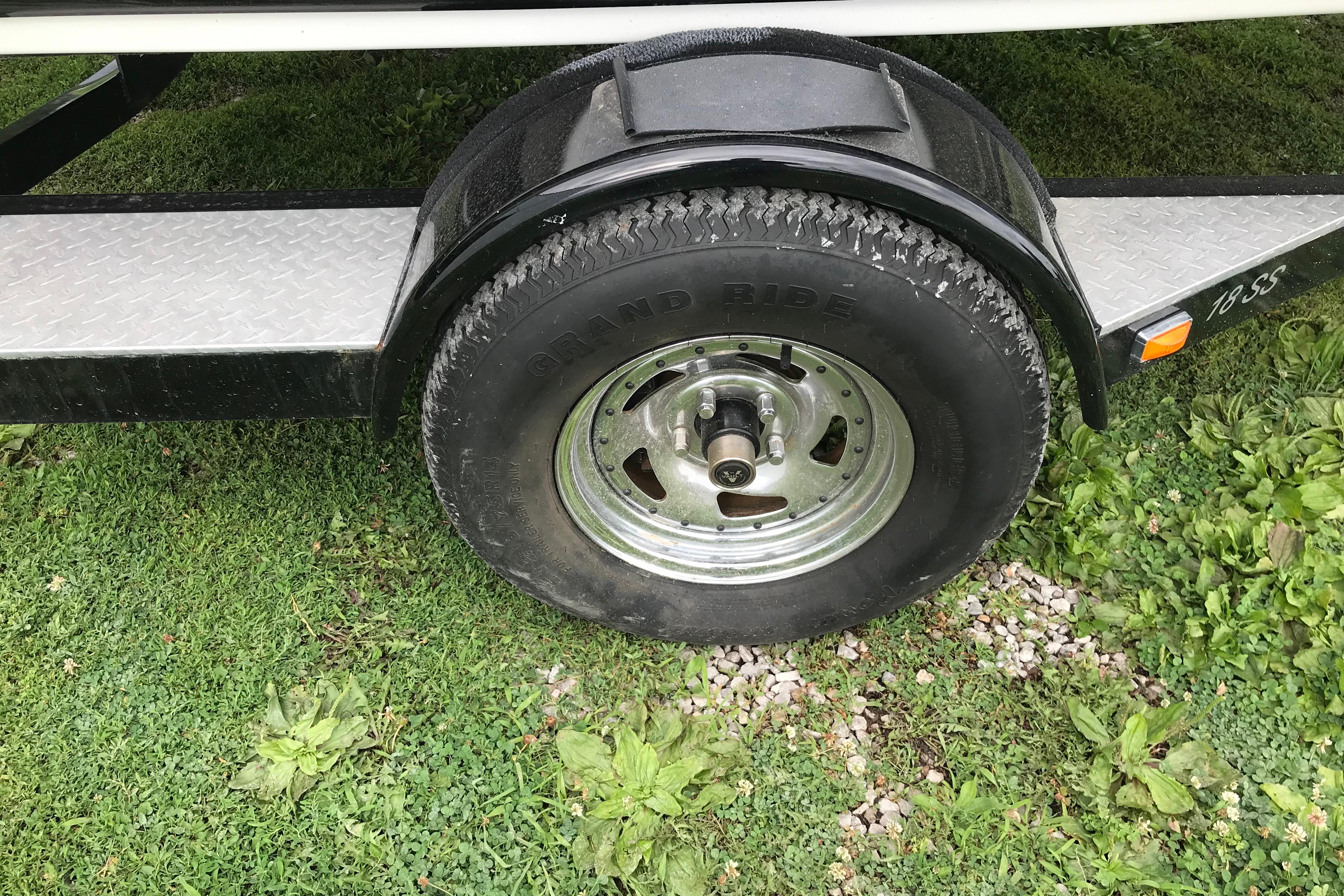 Trailer wheel of a 2015 Crownline 18 SS boat on grass.