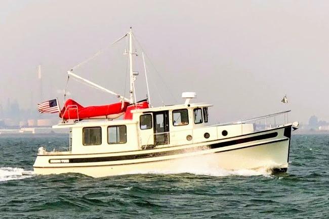 2002 Nordic Tug 37 cruising on open water with American flag.