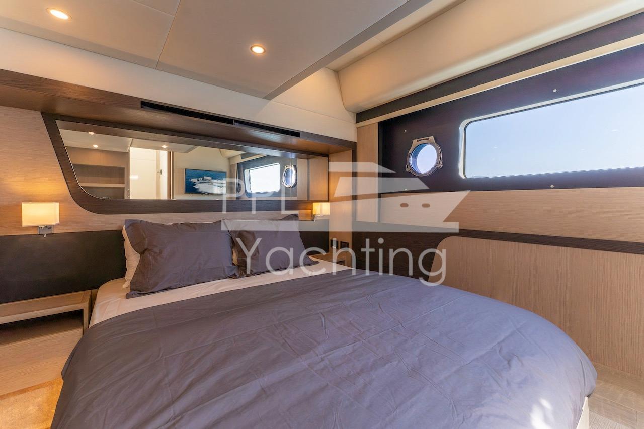 Luxurious bedroom interior of 2021 Absolute 47 Fly yacht with modern design and porthole window.