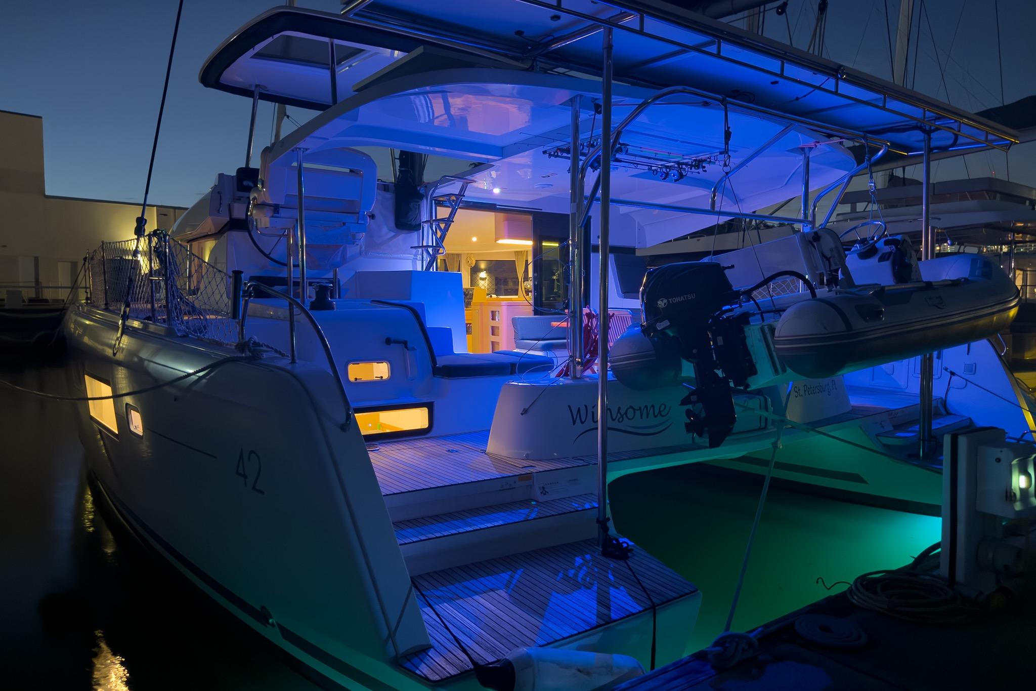 2018 Lagoon 42 catamaran illuminated at night, docked with blue ambient lighting.