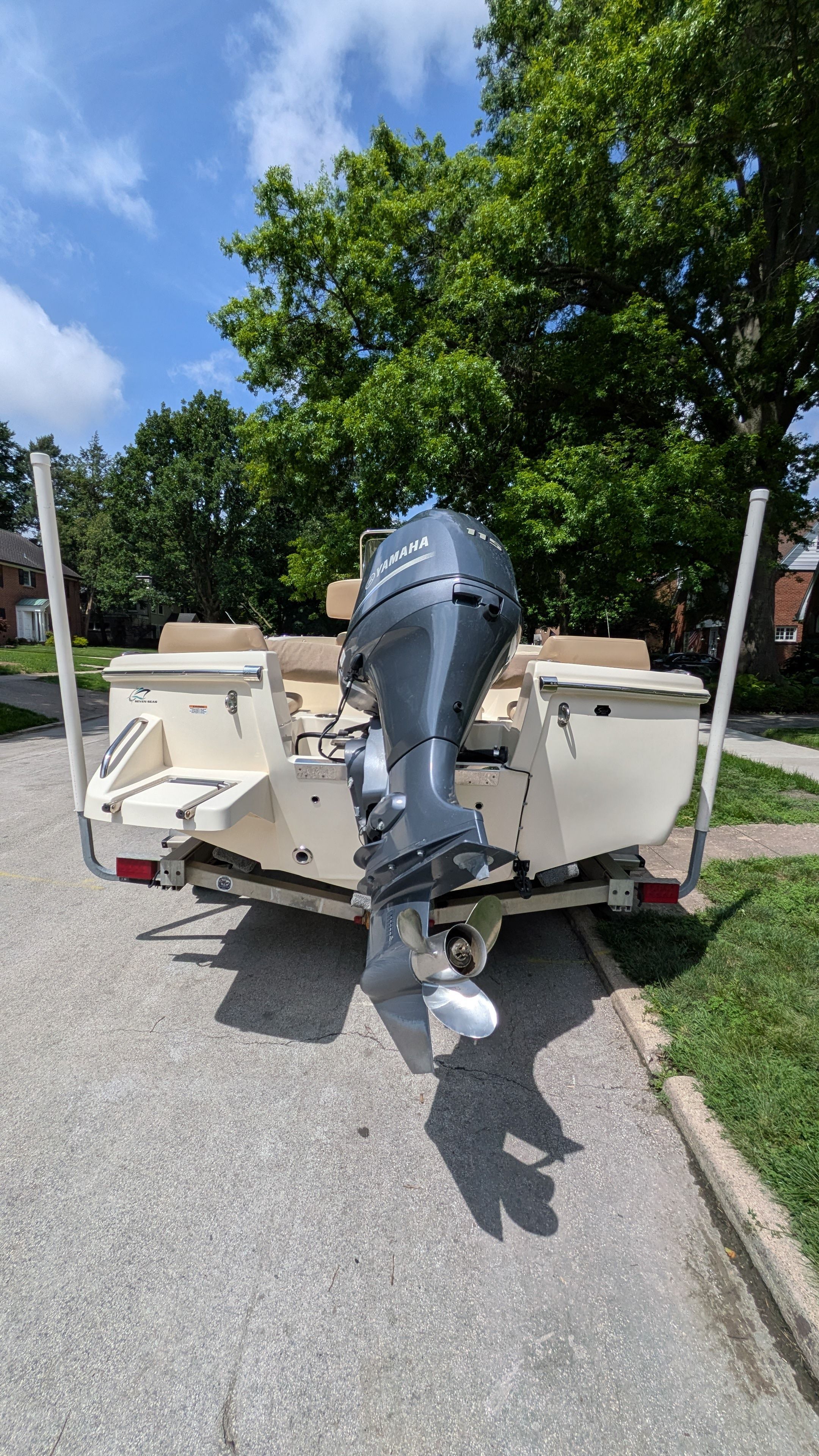 A 2021 Scout 195 Sportfish boat with an outboard motor, parked on a street.