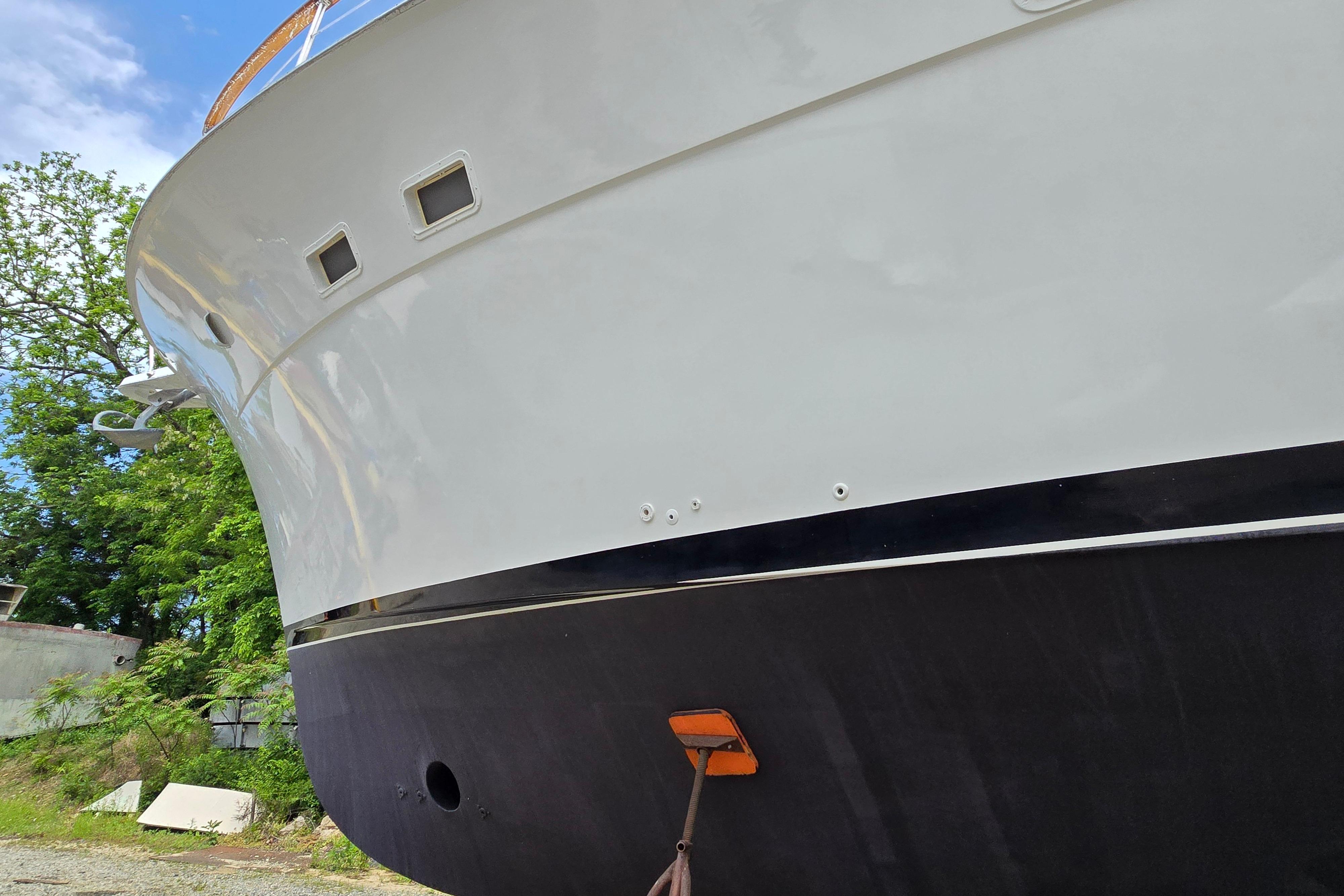 1980 Hatteras 70 Motor Yacht hull, docked with trees in the background.