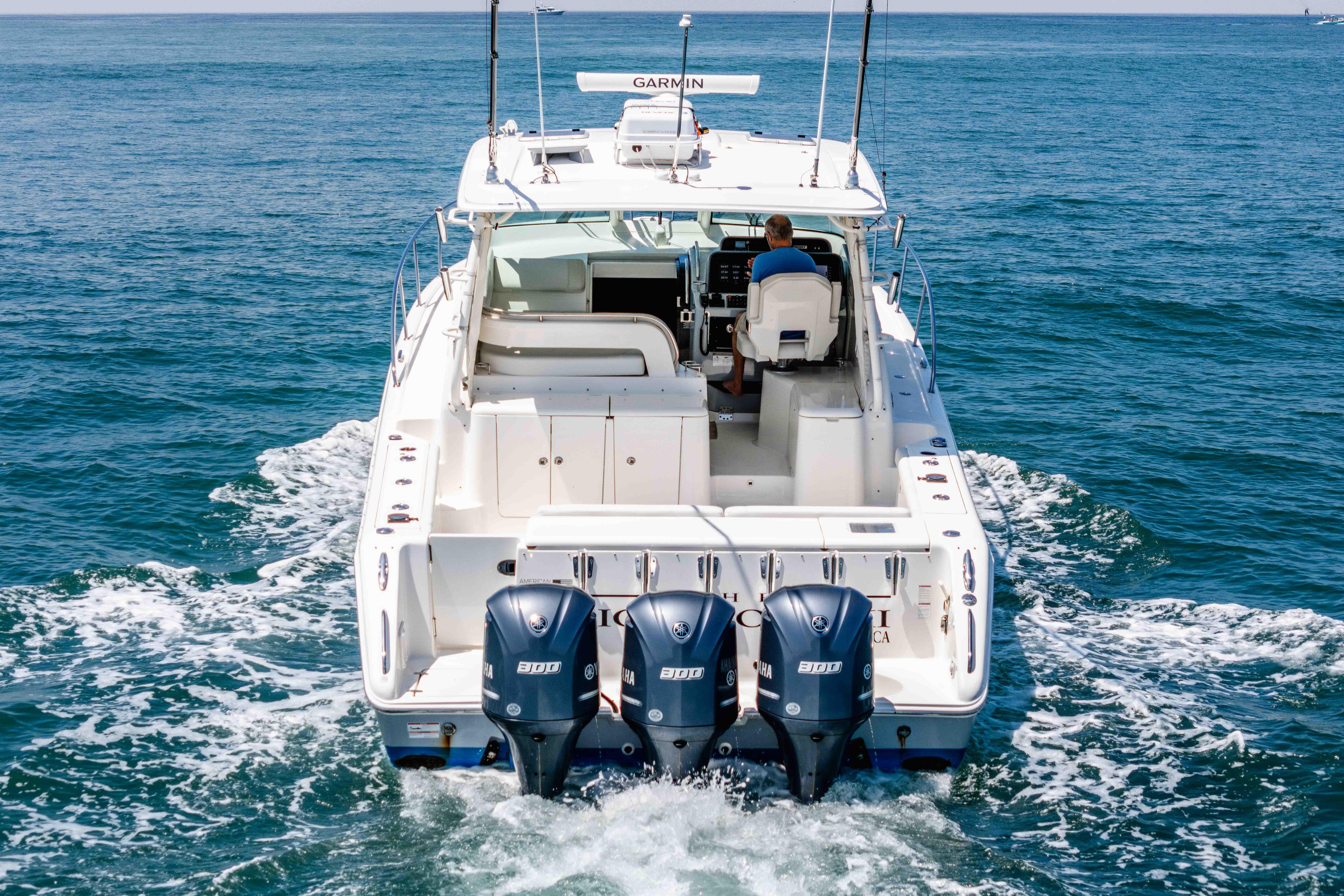 2022 Pursuit OS 385 Offshore boat cruising on open water with triple Yamaha engines.