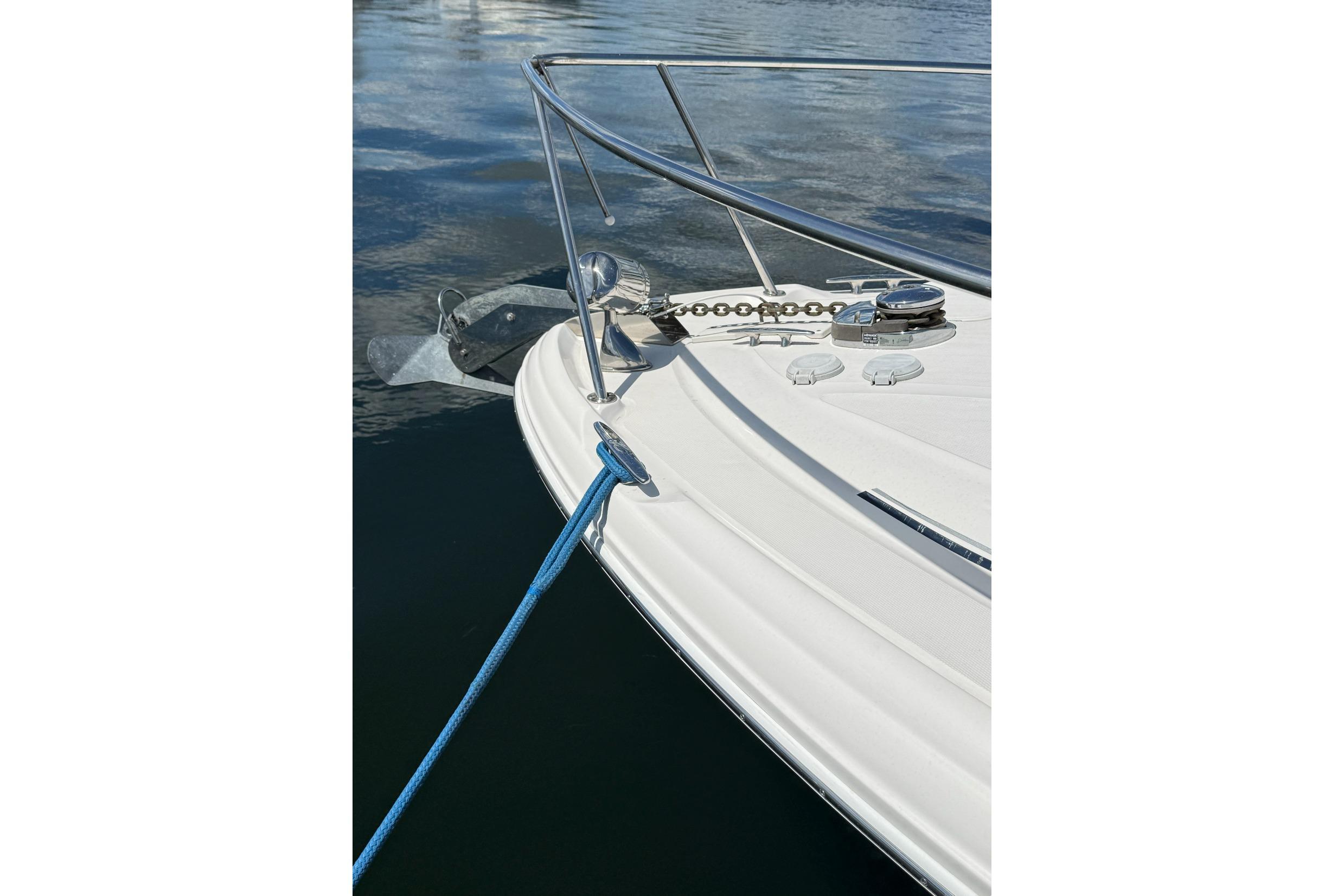 Bow of 2006 Sea Ray 300 Sundancer with anchor and blue mooring line.