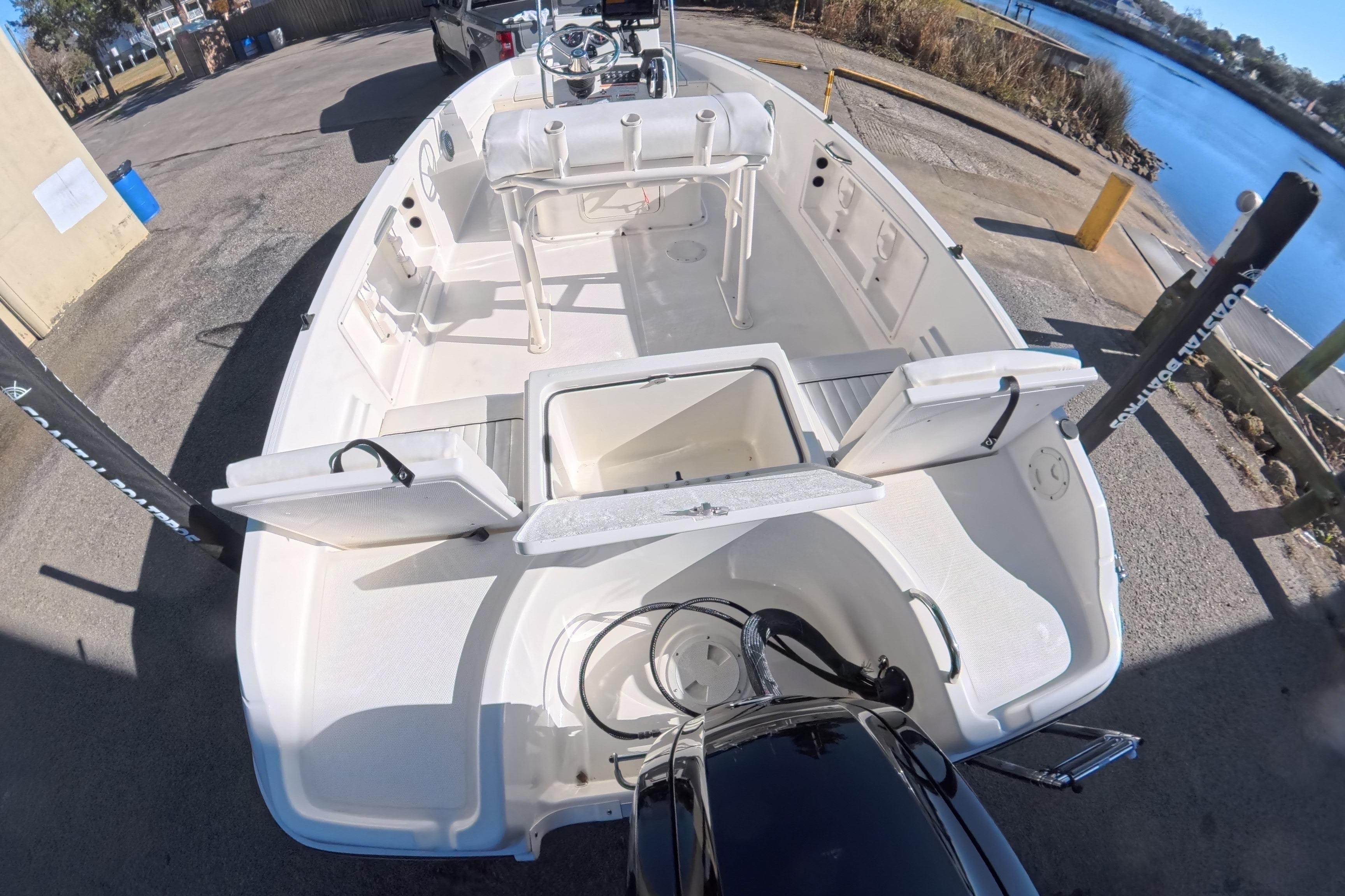 2023 Trophy T-18 boat with open storage compartments, docked by a serene waterfront.