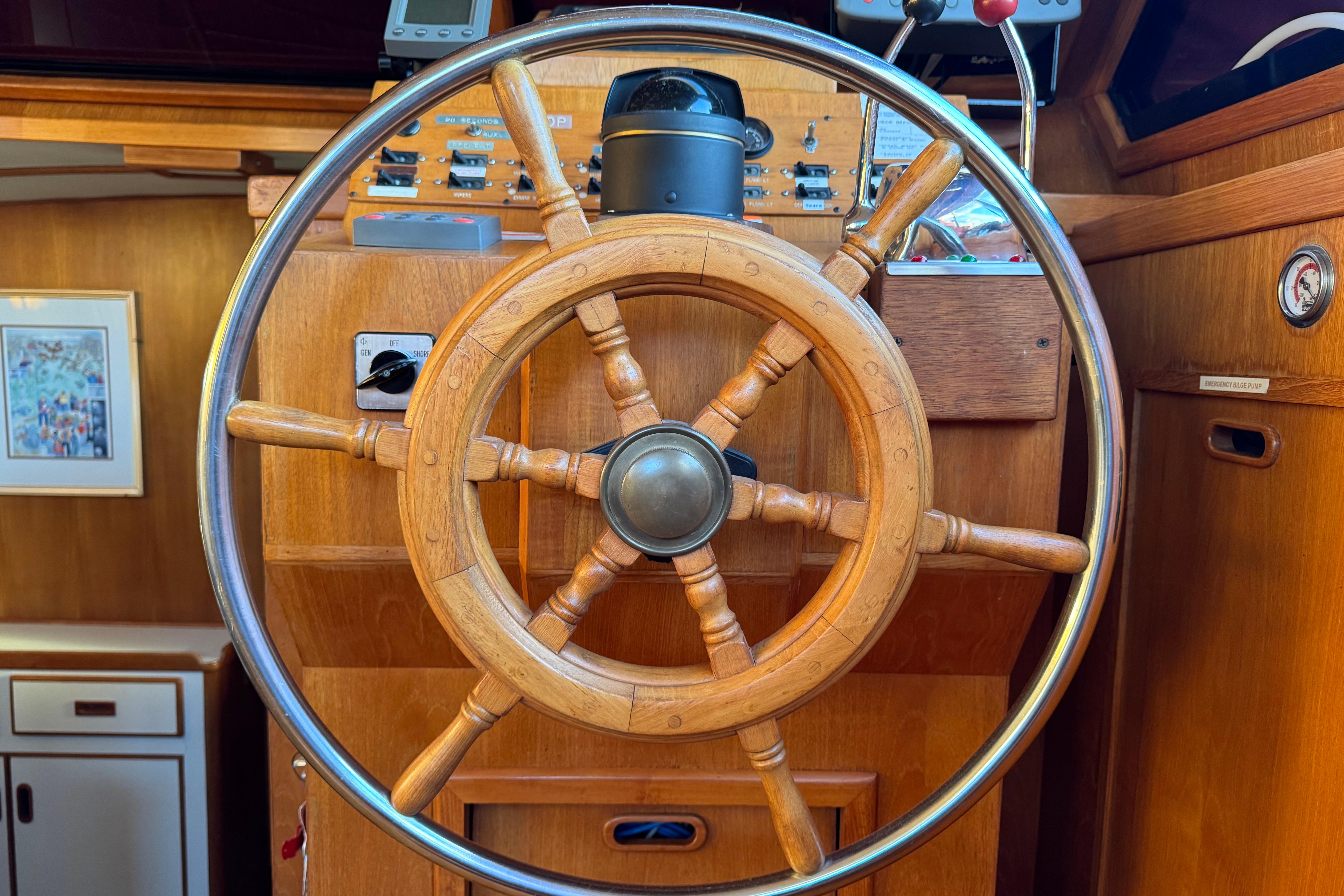 Wooden ship wheel on a 1987 President 37 yacht, surrounded by navigation controls.