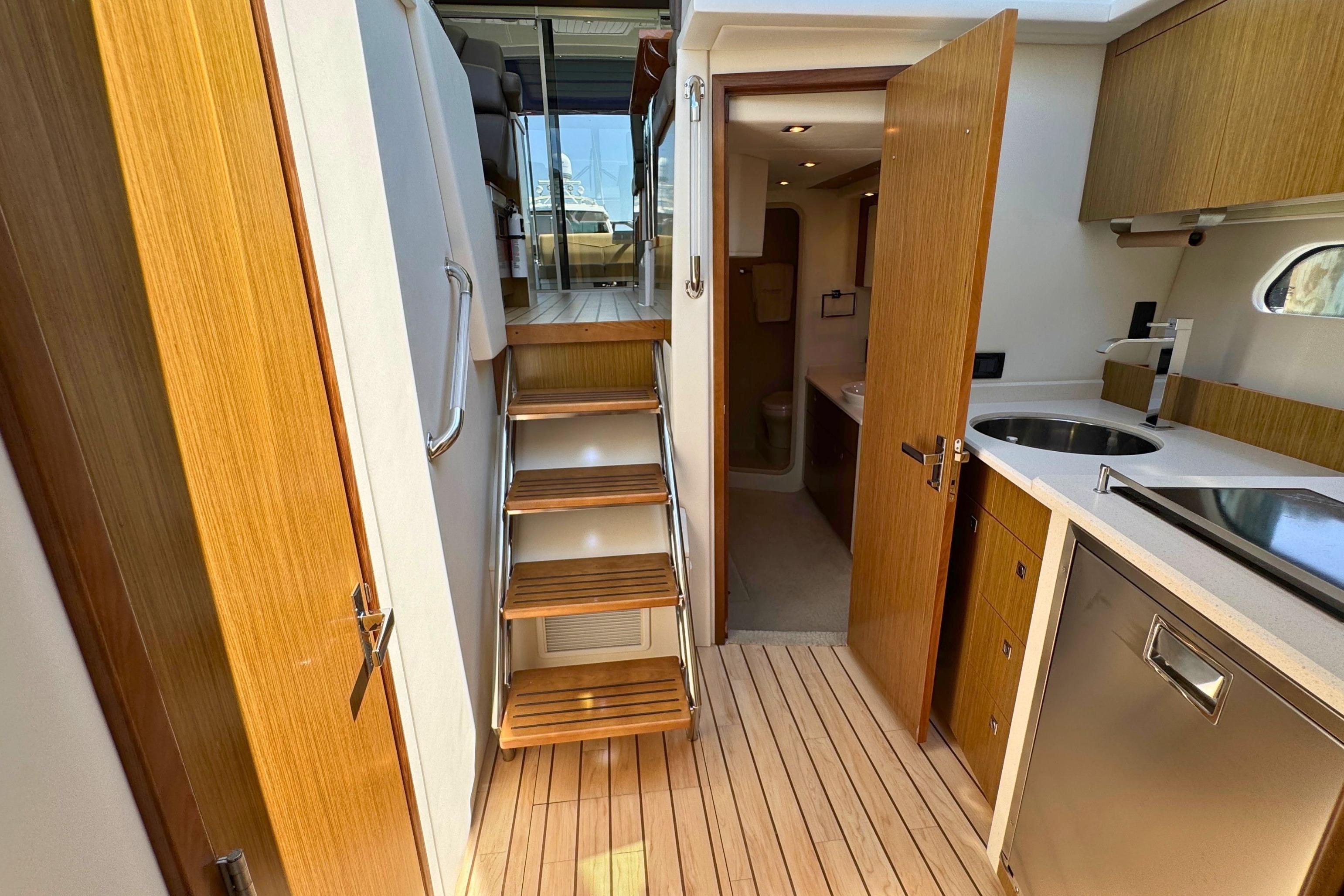 Interior of 2014 Cruisers Yachts 41 Cantius, featuring wooden stairs and modern kitchenette.