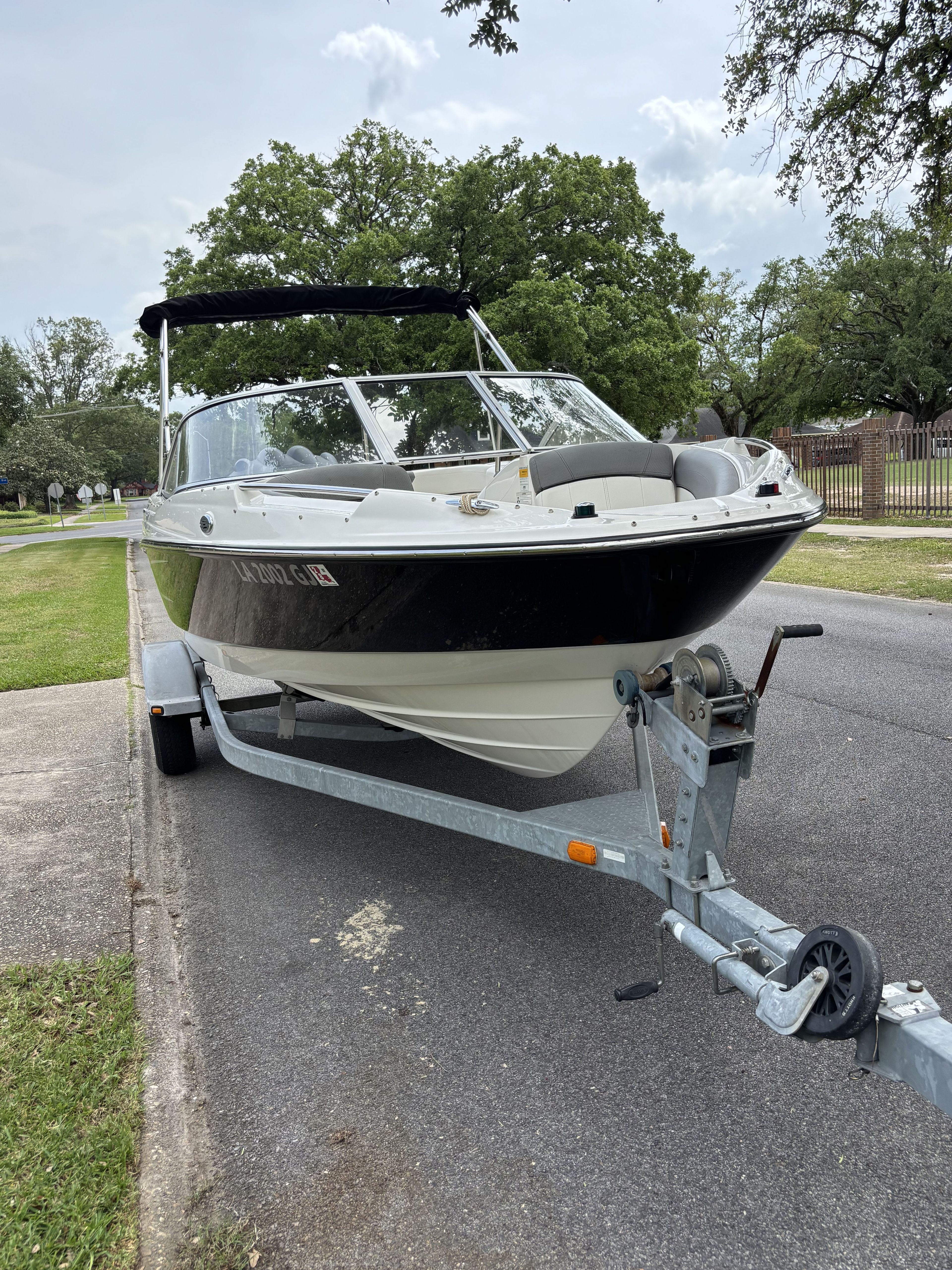A 2015 Bayliner 215 Bowrider on a trailer parked by the roadside.