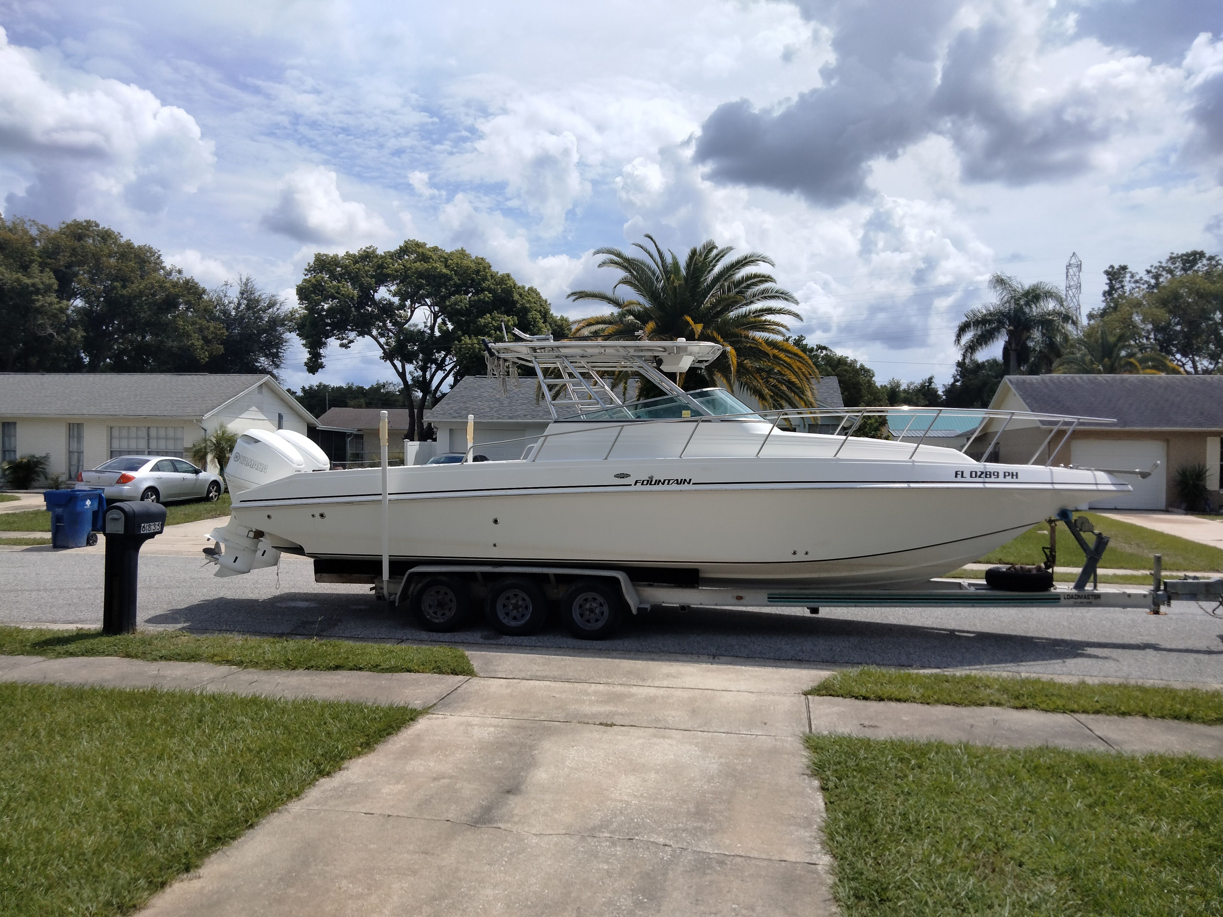 A 1995 Fountain 31 SFC boat on a trailer in a residential area.