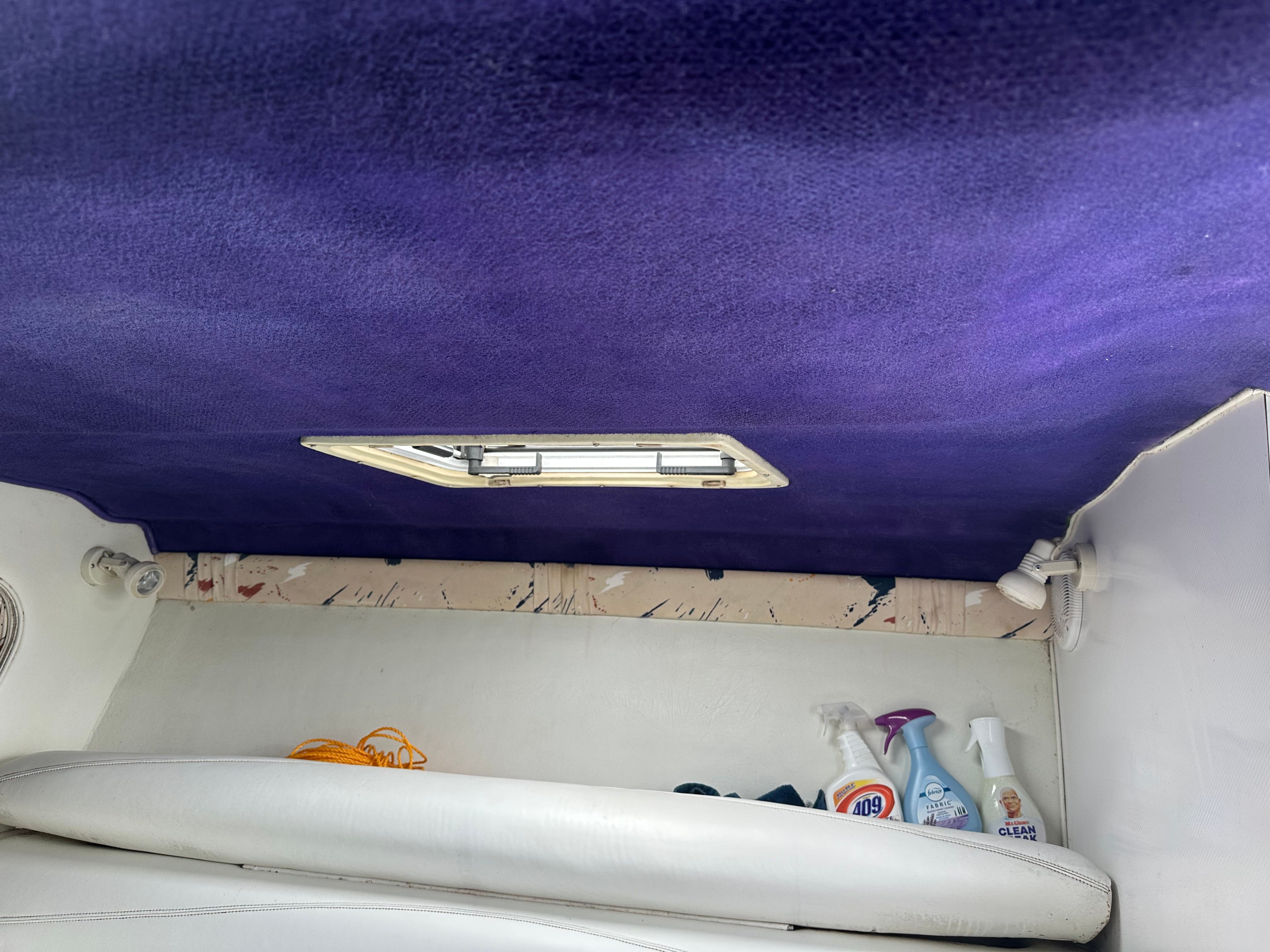 Interior of a boat with a purple ceiling and white seating.