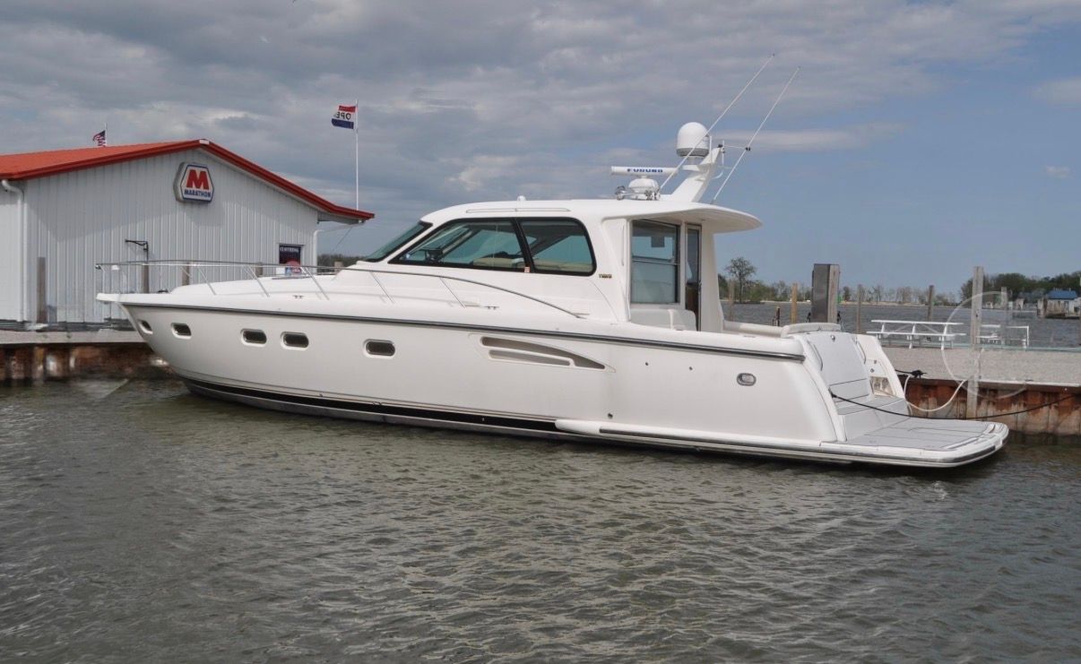 A 2005 Tiara Yachts 5200 Sovran docked. It is white with an enclosed cockpit.