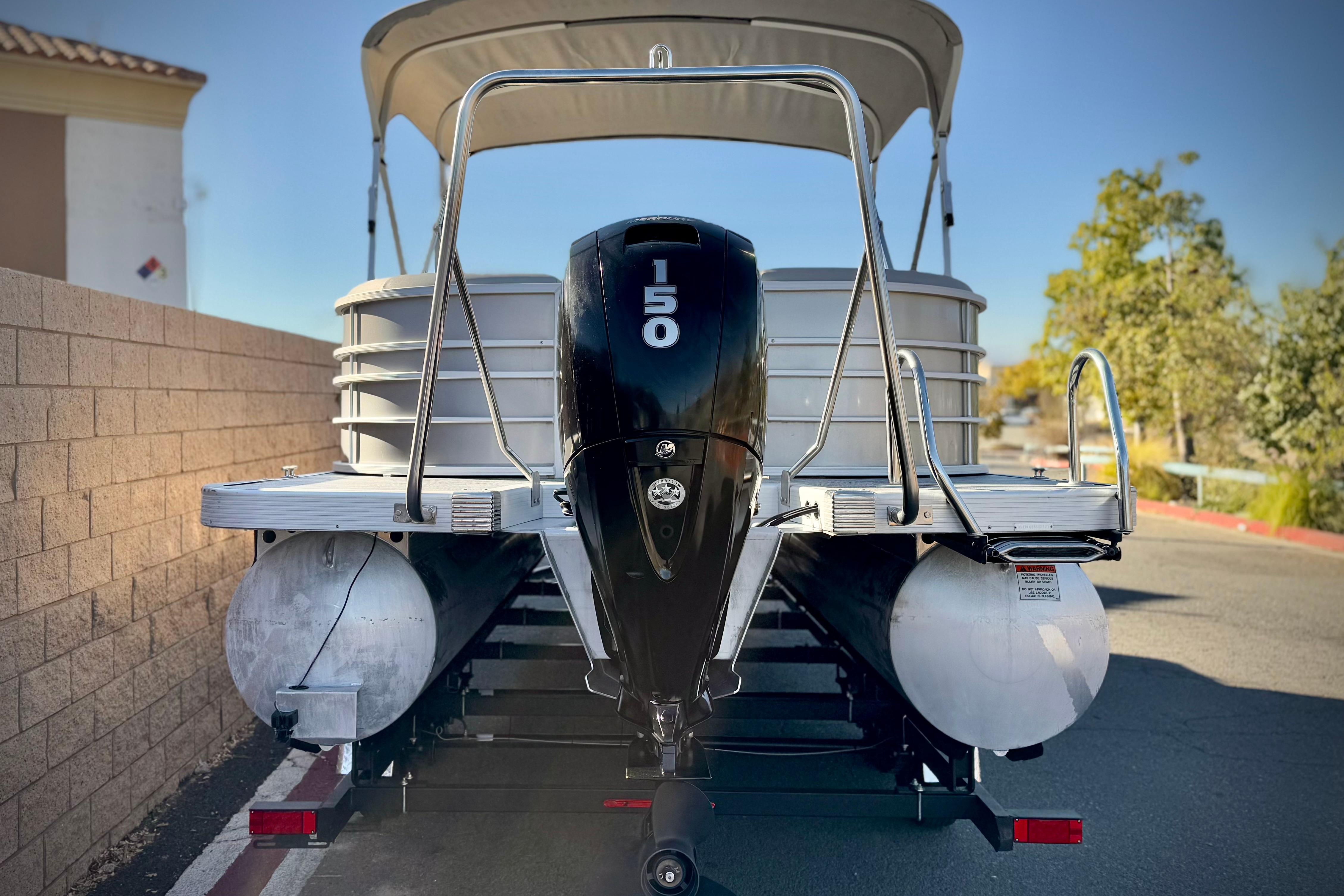 2021 Bennington 23LSR pontoon boat with 150 HP engine, parked on a sunny day.