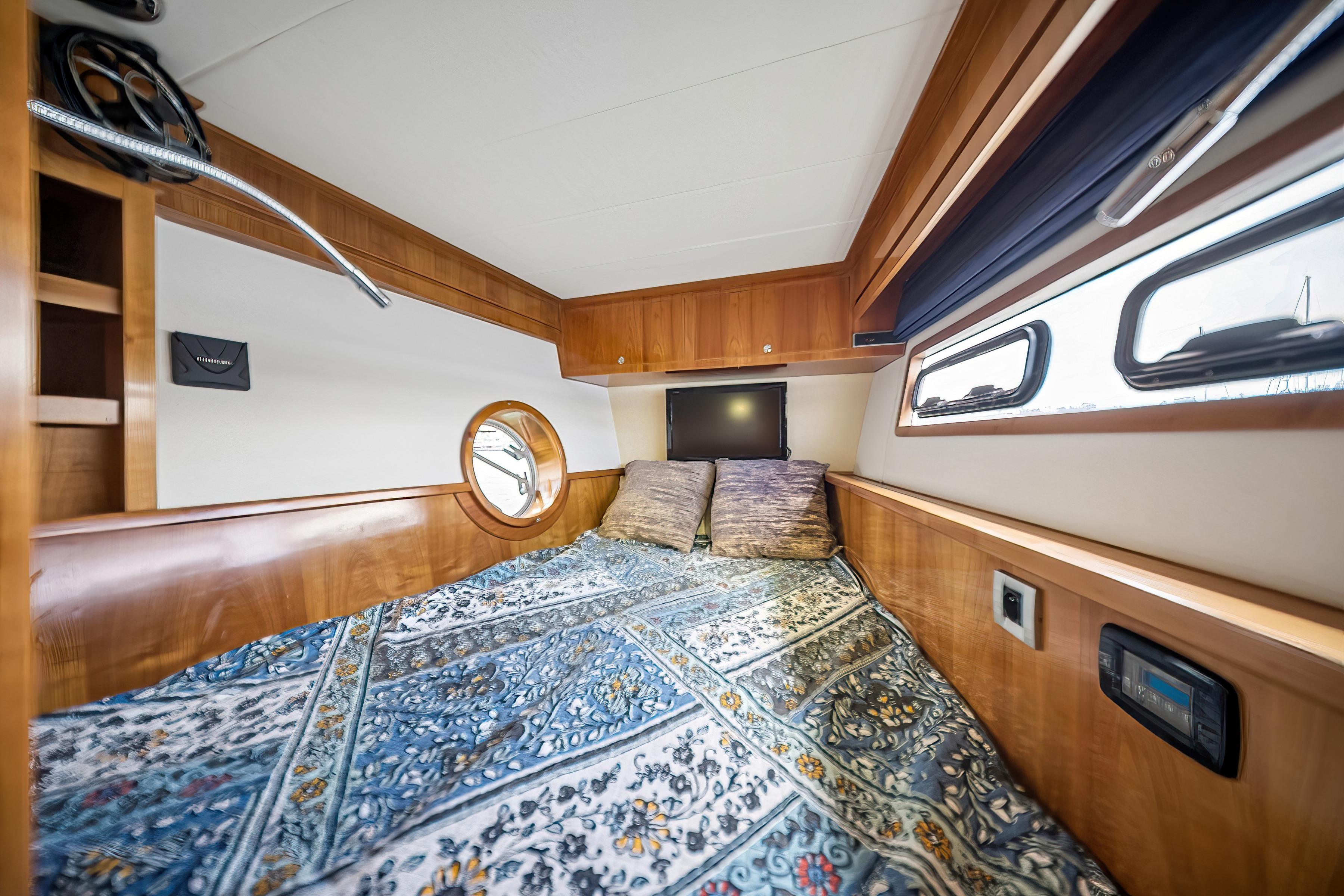Luxurious cabin interior of 2009 Catana 65 yacht with cozy bedding and wooden accents.
