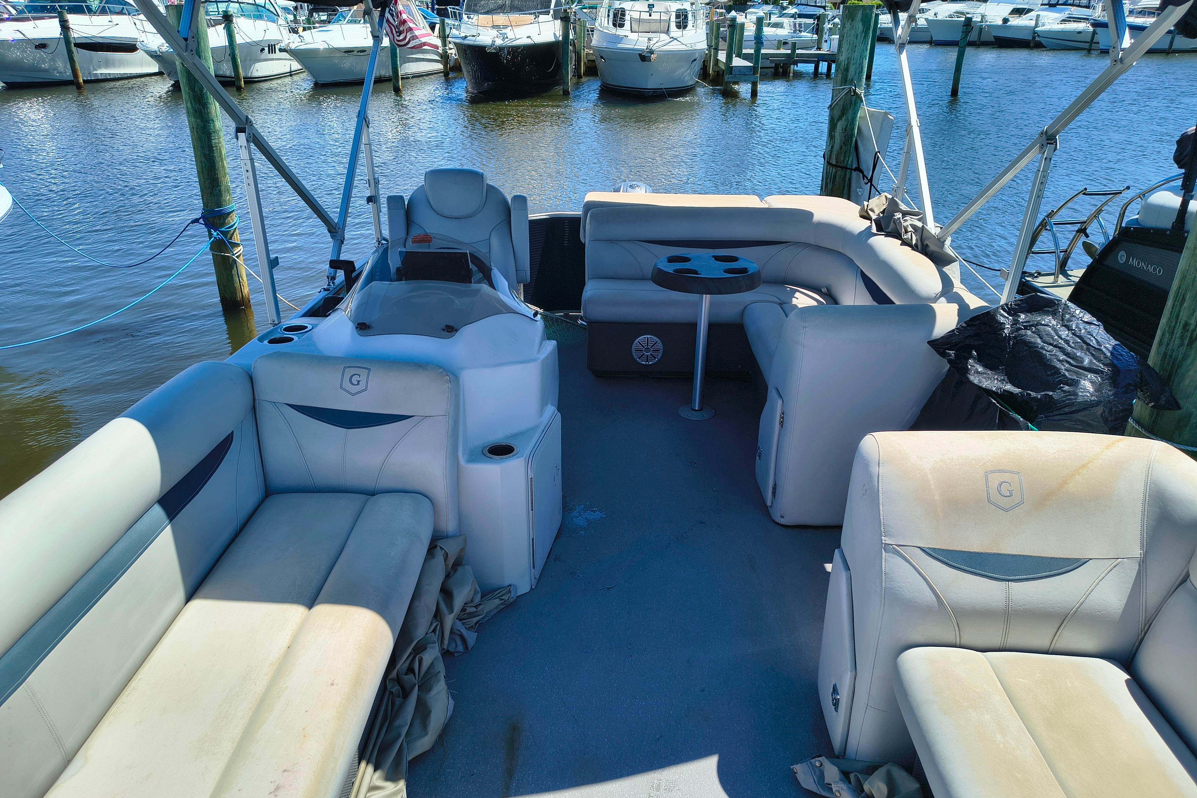 Interior of a 2018 Godfrey Sweetwater 2286 C pontoon boat at a marina.