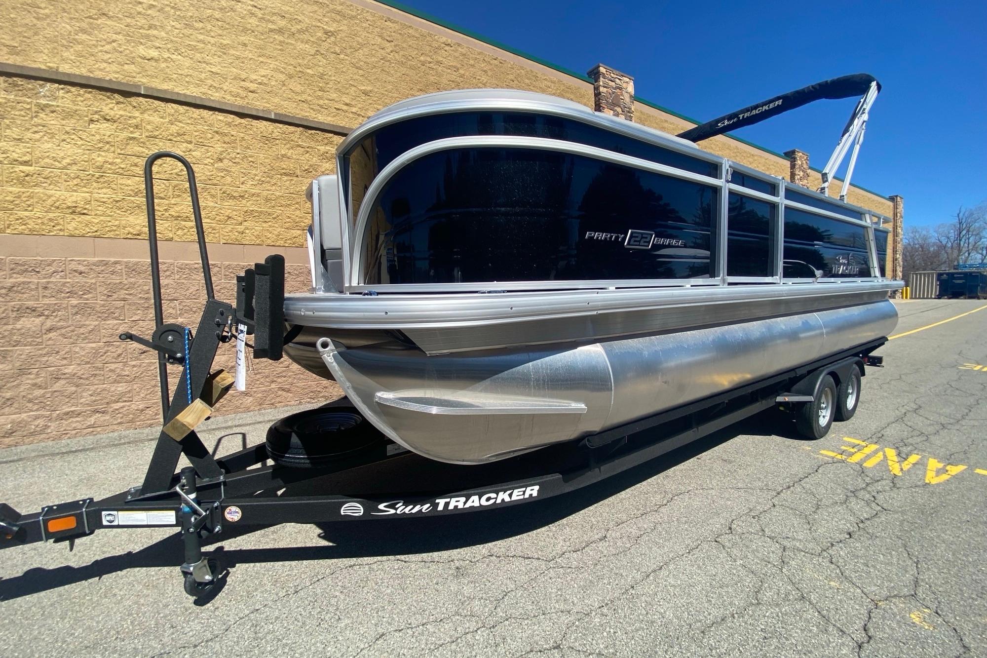 2026 Sun Tracker Party Barge 22 RF DLX pontoon boat on trailer, parked outdoors.