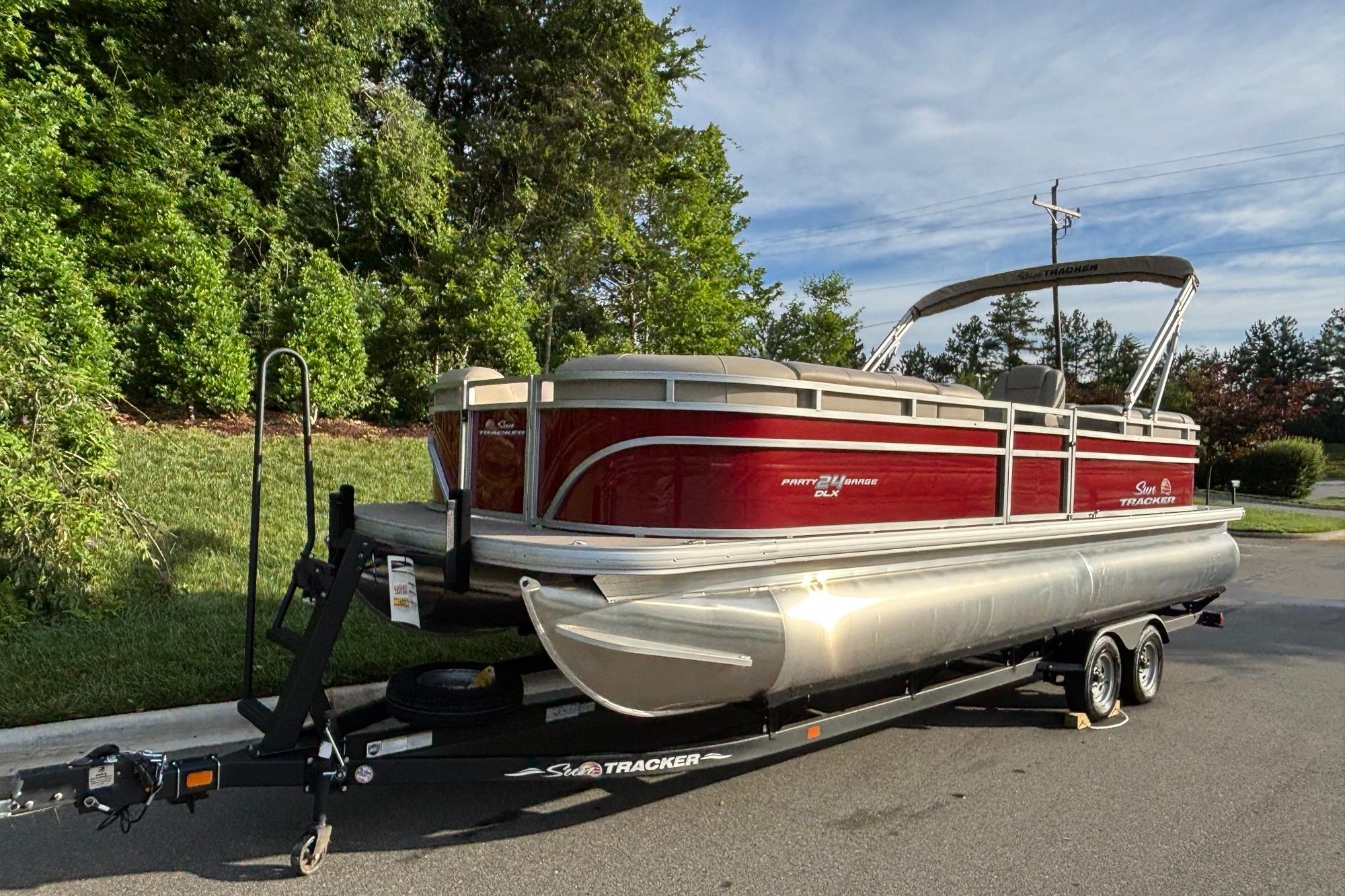 2025 Sun Tracker Party Barge 24 DLX pontoon boat on trailer, parked outdoors.