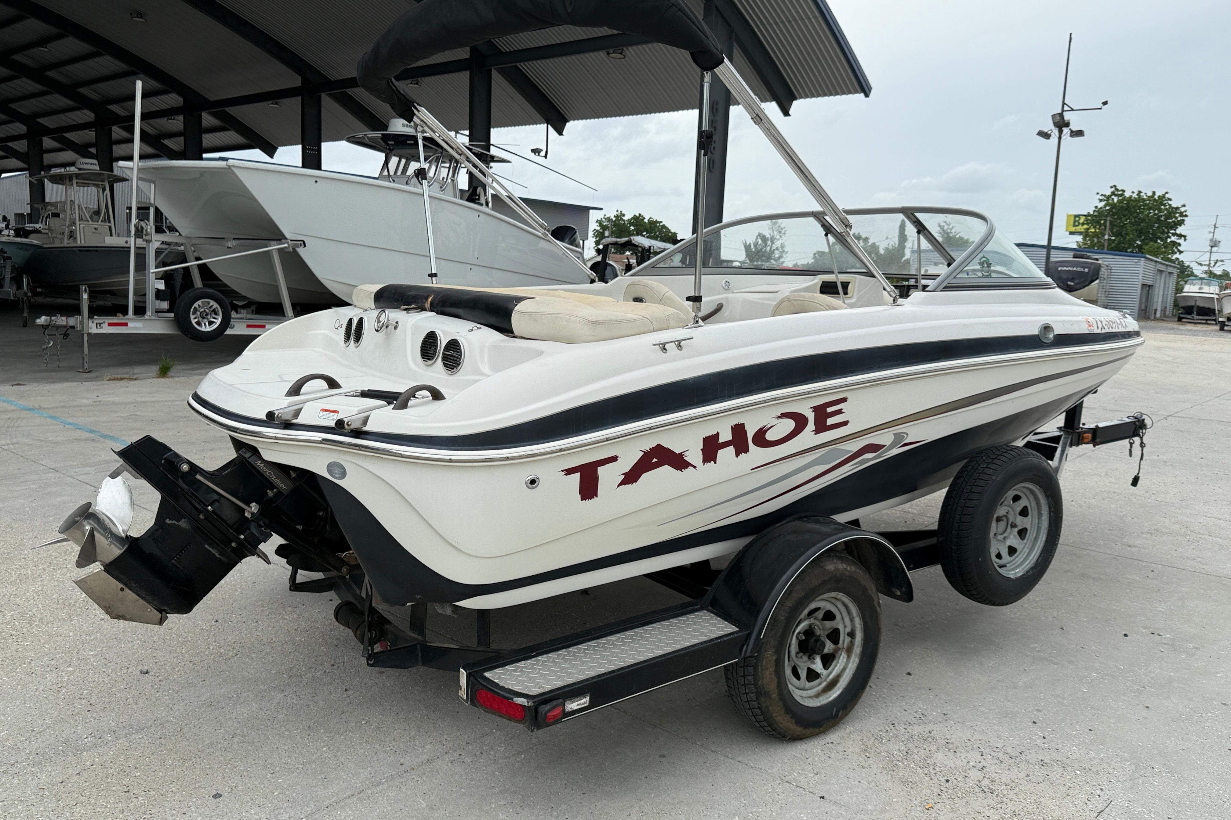 2010 Tahoe Q4 boat on trailer, parked outdoors near other boats.