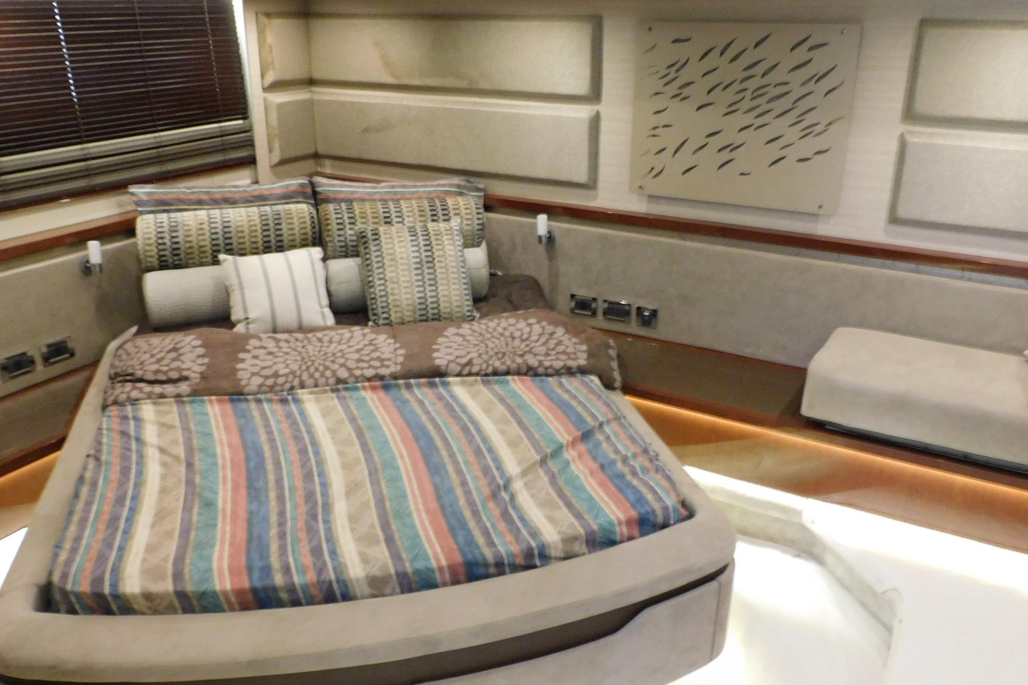 Luxurious 2019 Sea Ray L550 yacht bedroom with striped bedding and decorative pillows.