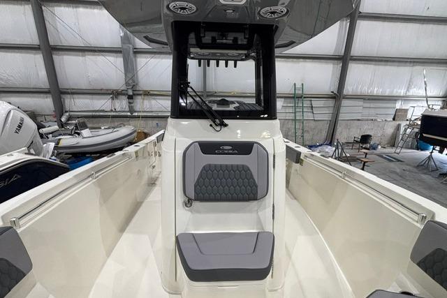 2026 Cobia 245 Center Console boat interior with seating and console in a storage facility.