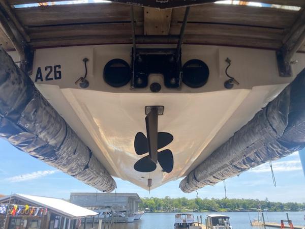 1998 Malibu Response boat underside with propeller, docked by a scenic waterfront.