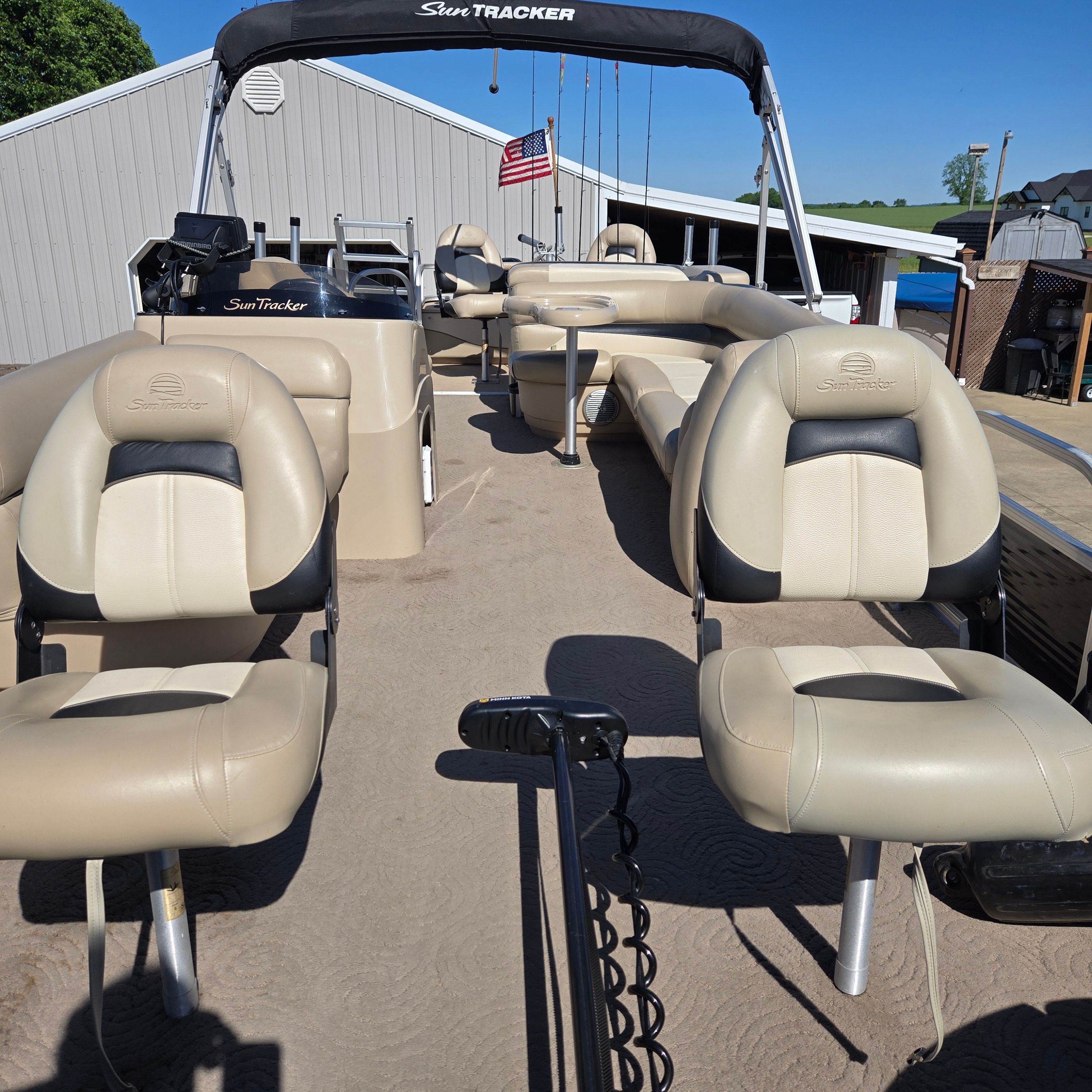 The image shows the deck of a 2012 Sun Tracker Fishin' Barge 24 DLX with beige seats.