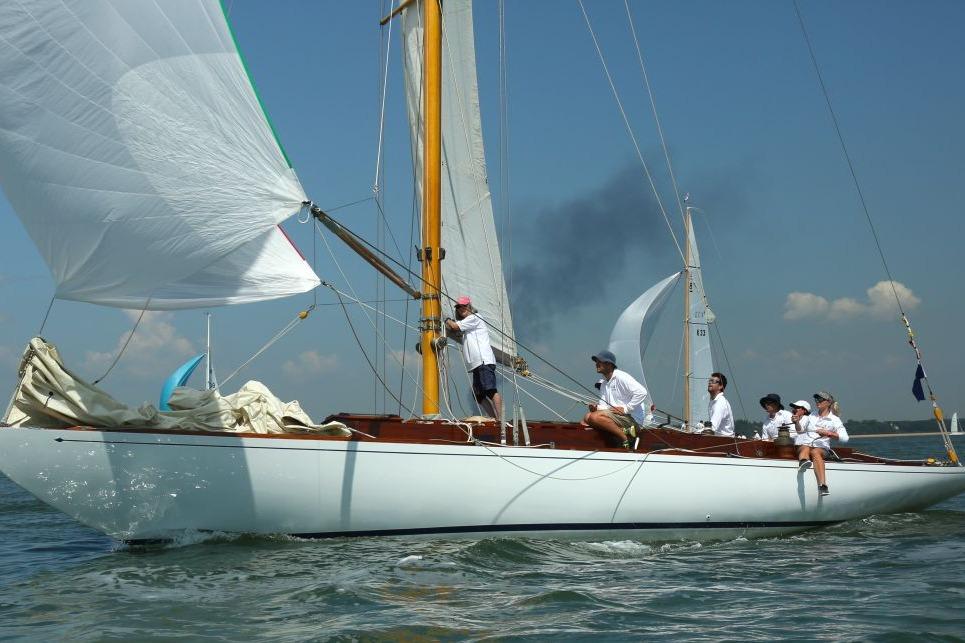 Sailing crew on a 1939 Classic Custom yacht navigating calm waters under clear skies.