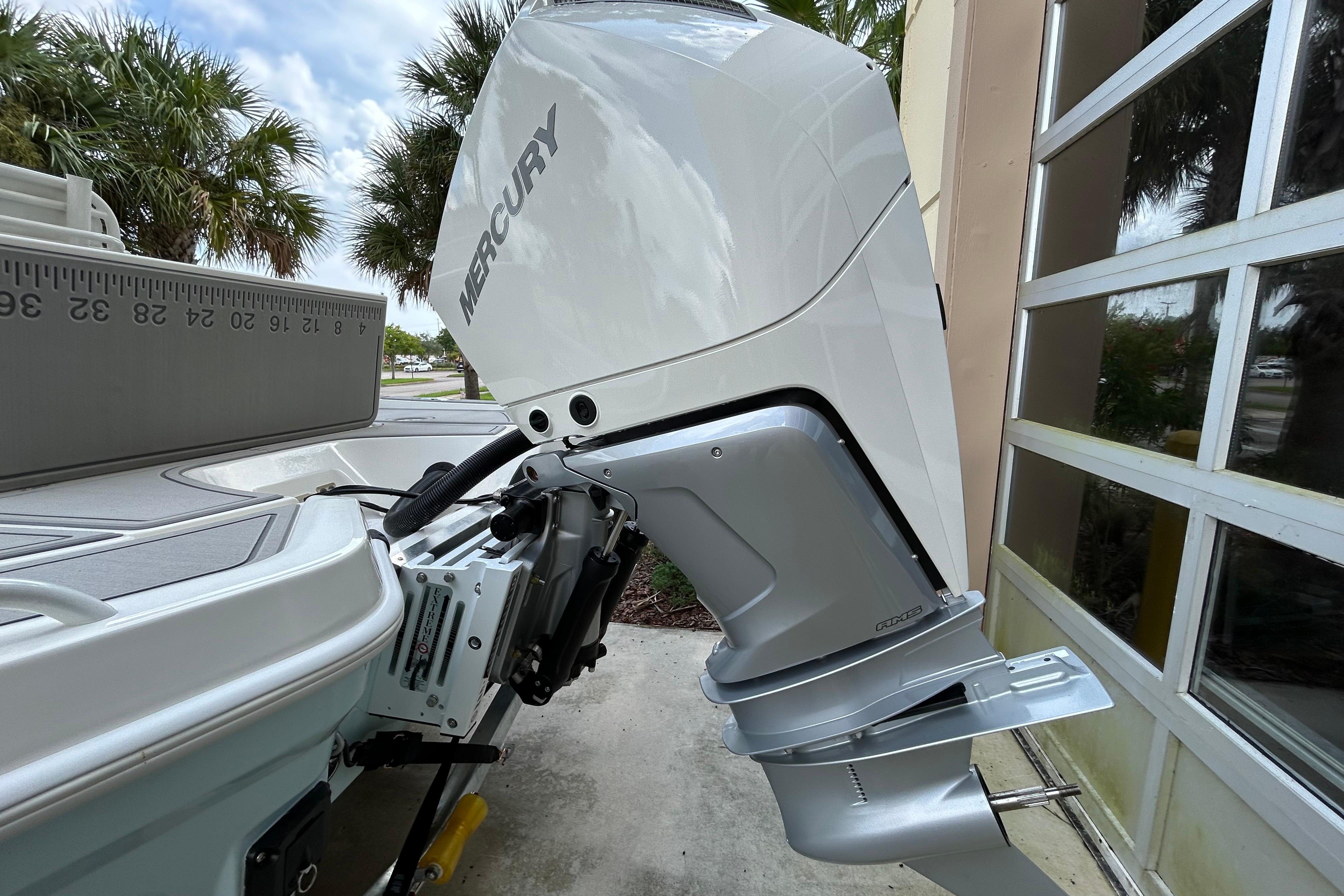 2025 Mako 24 APEX boat with Mercury outboard motor, parked near palm trees.