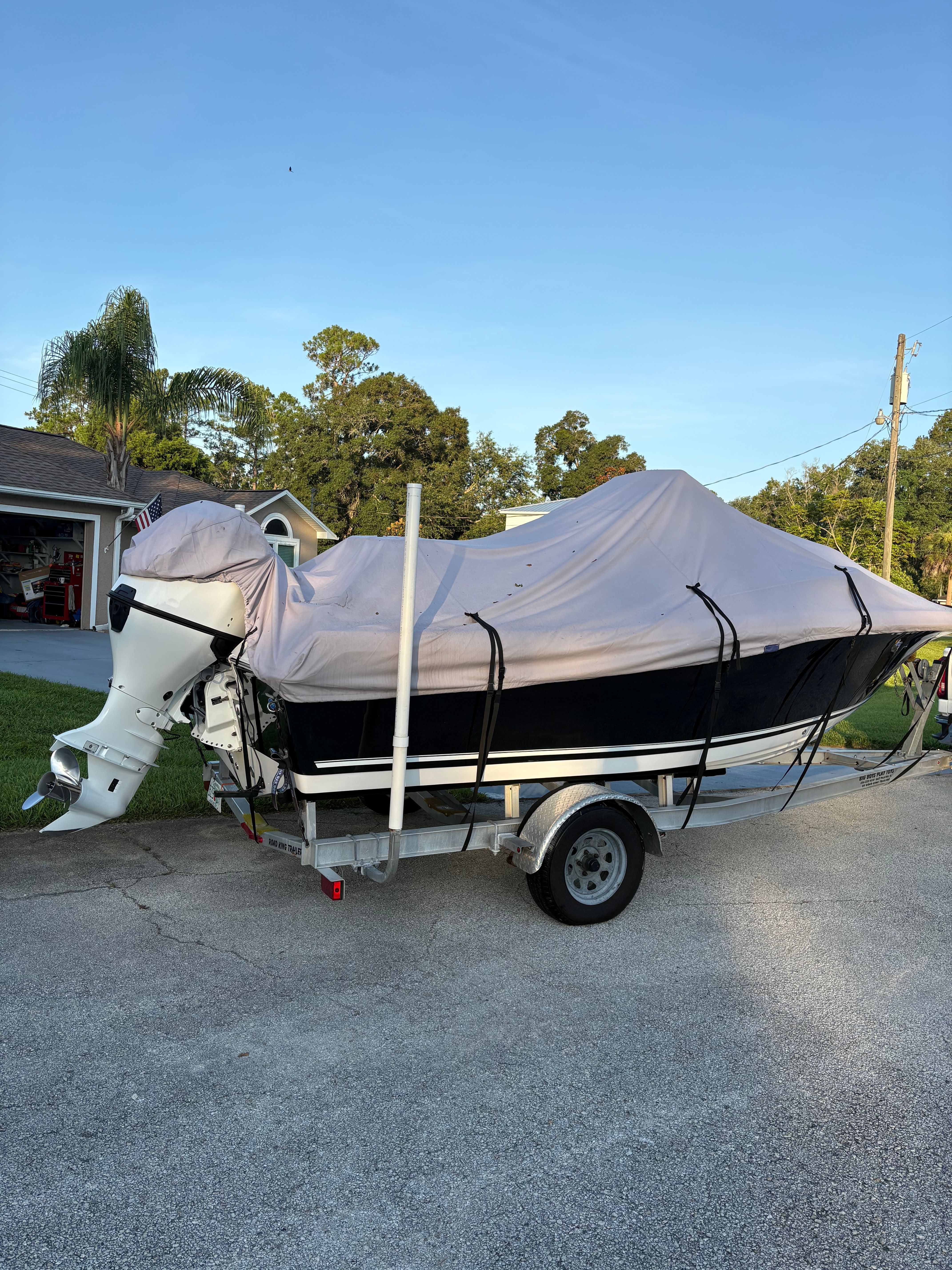 A covered boat on a trailer is parked in a residential area.