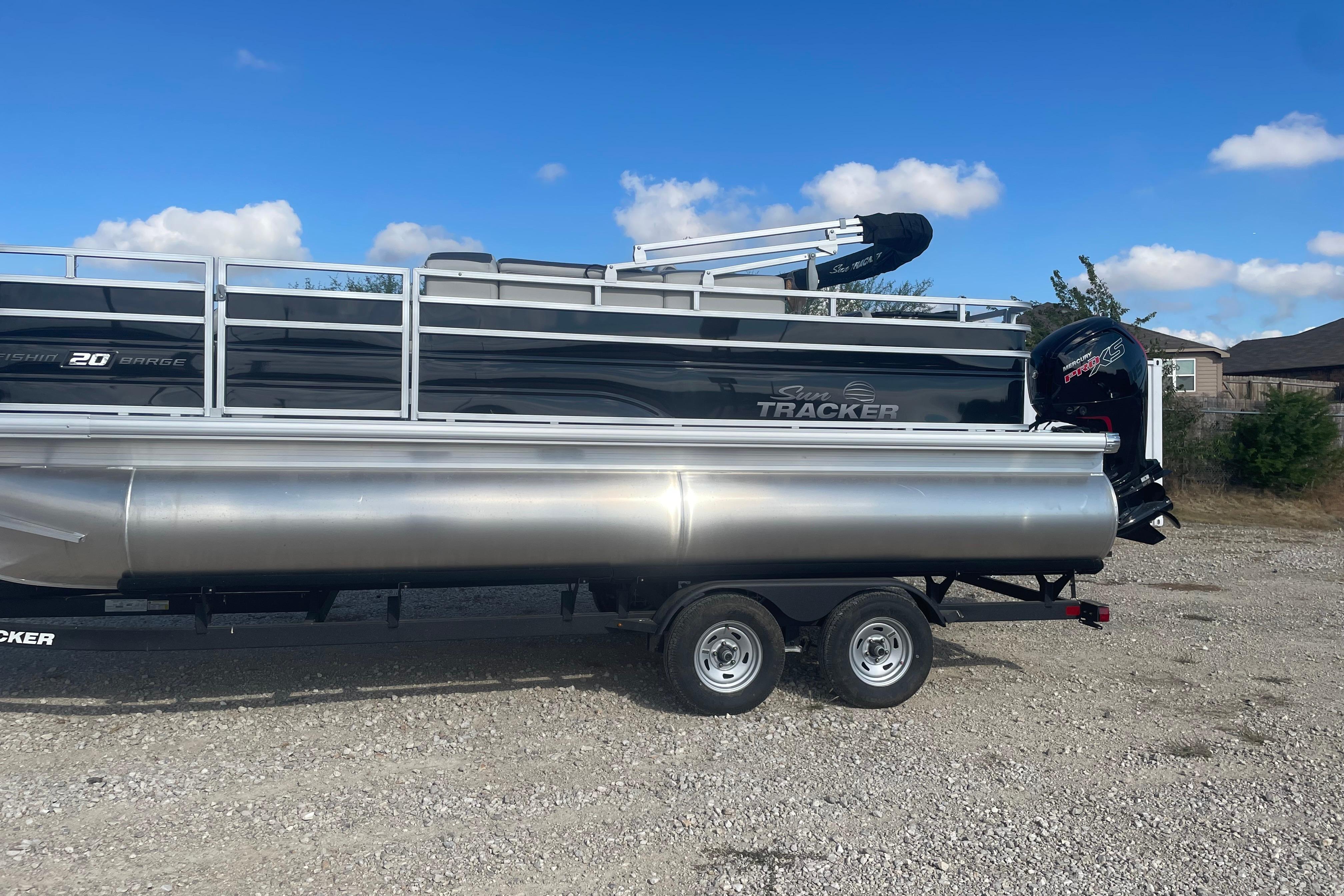 2026 Sun Tracker Fishin' Barge 20 DLX pontoon boat on trailer, outdoor setting.