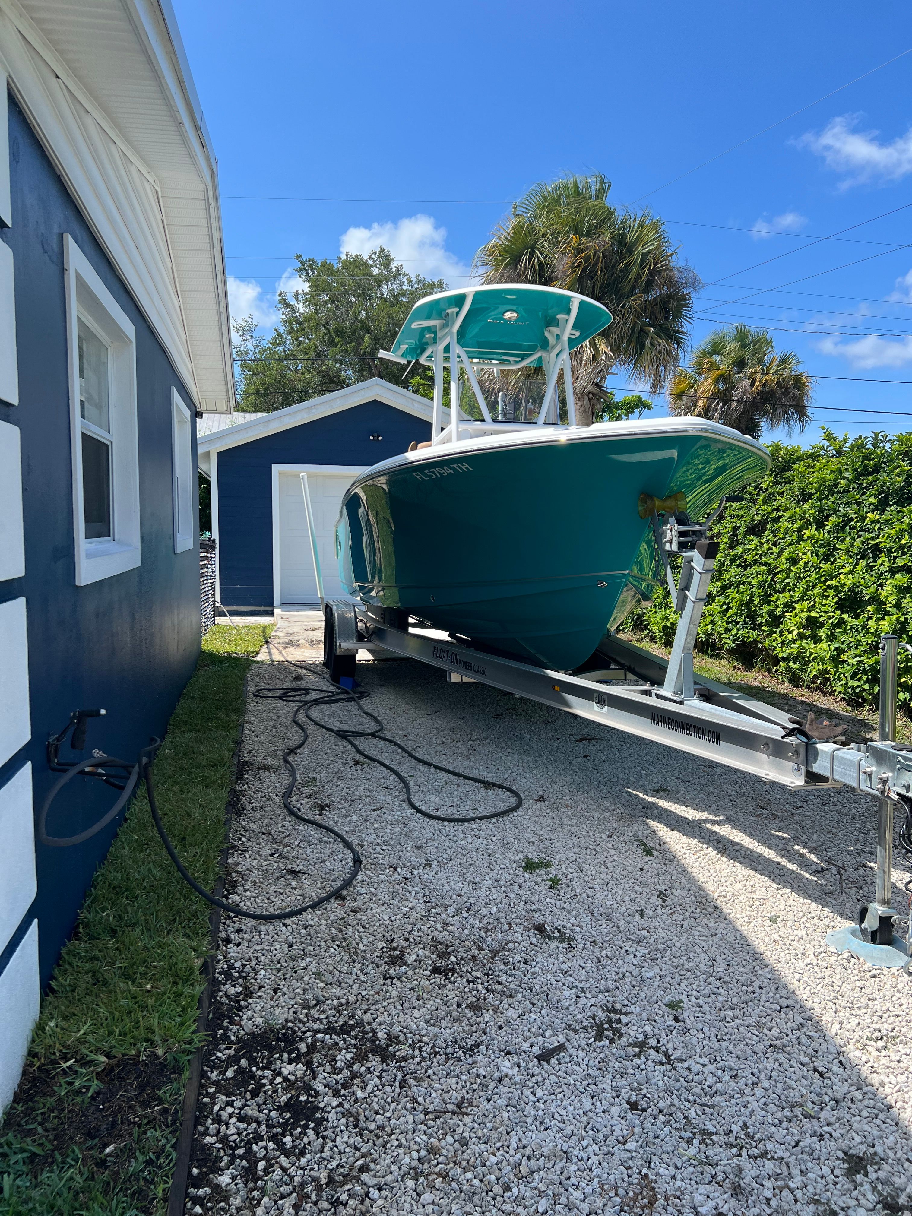 2022 Sea Hunt Ultra 234 boat on trailer beside house.