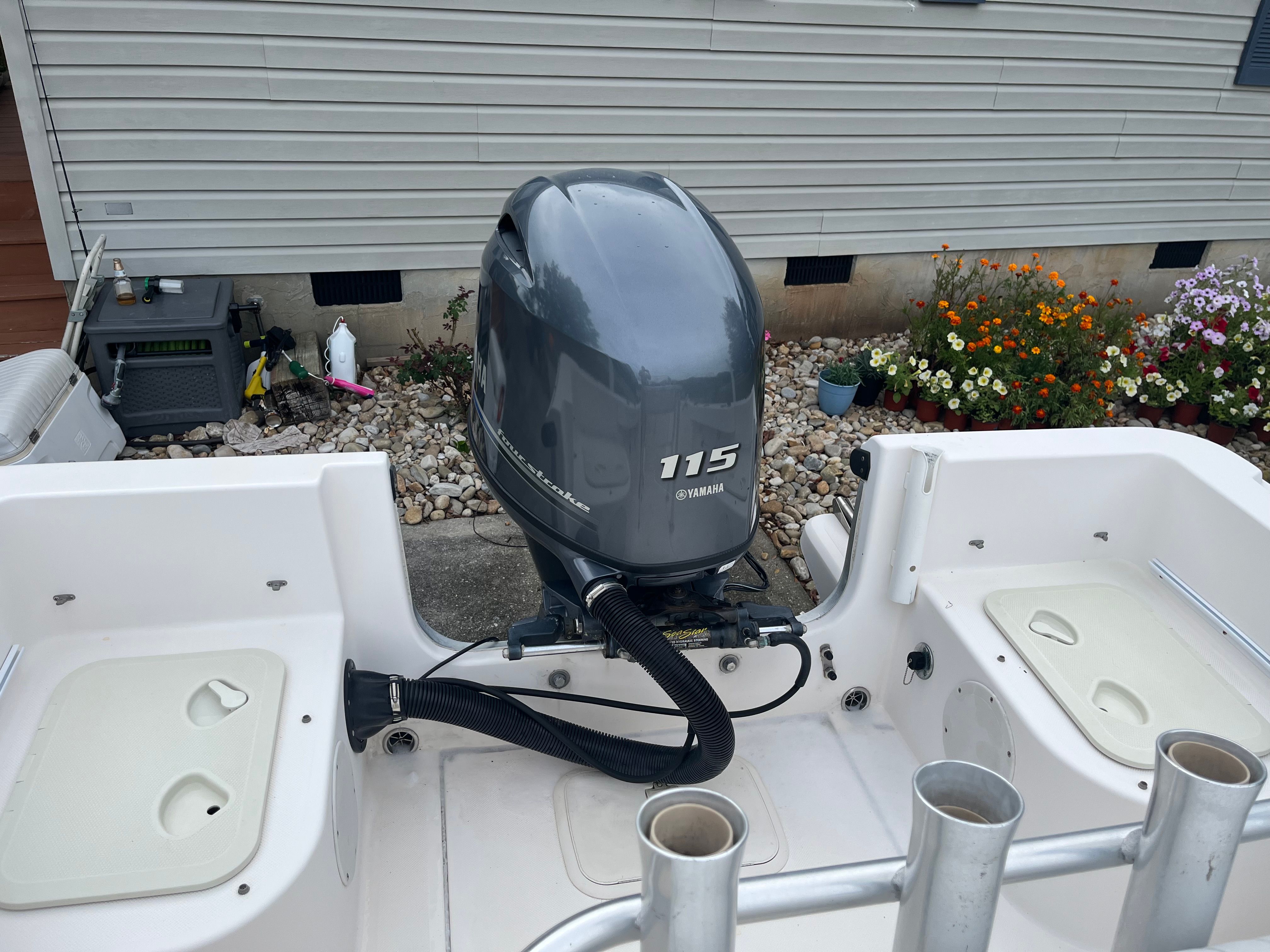 A boat with a Yamaha 115 outboard motor, surrounded by flowers and a building.