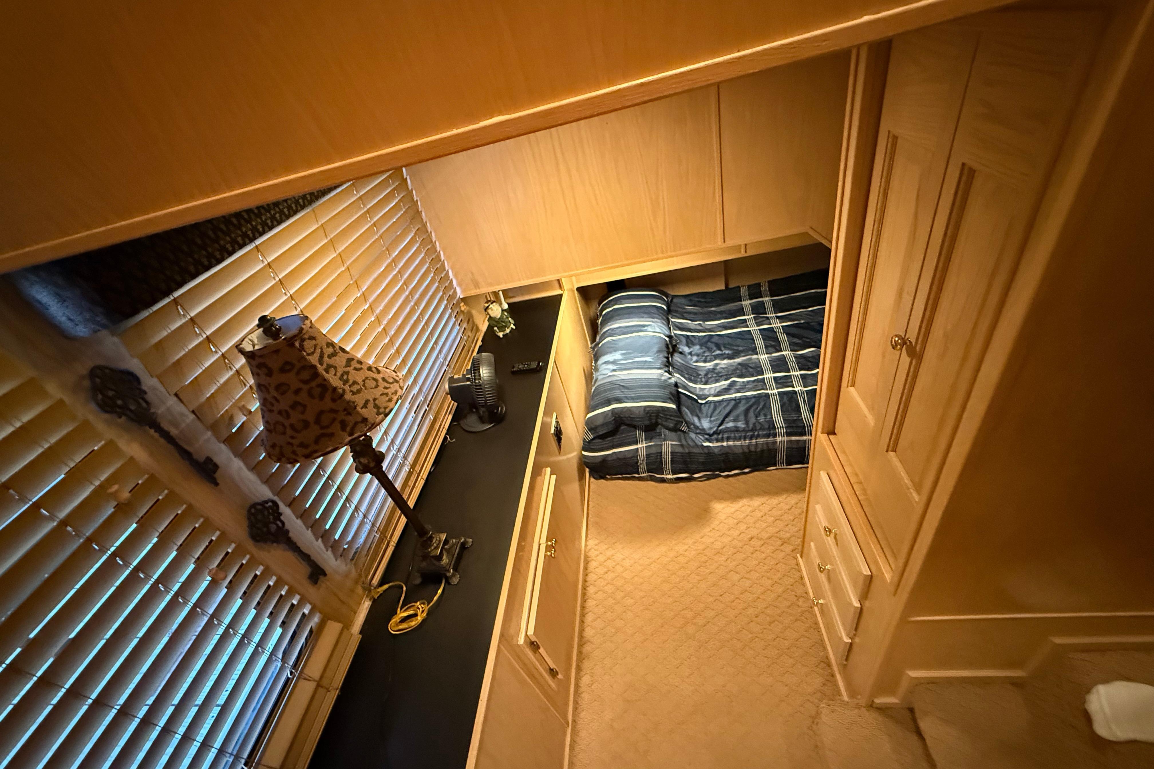 Cozy bedroom in 1998 Sumerset 16x76 houseboat with plaid bedding and wooden furnishings.