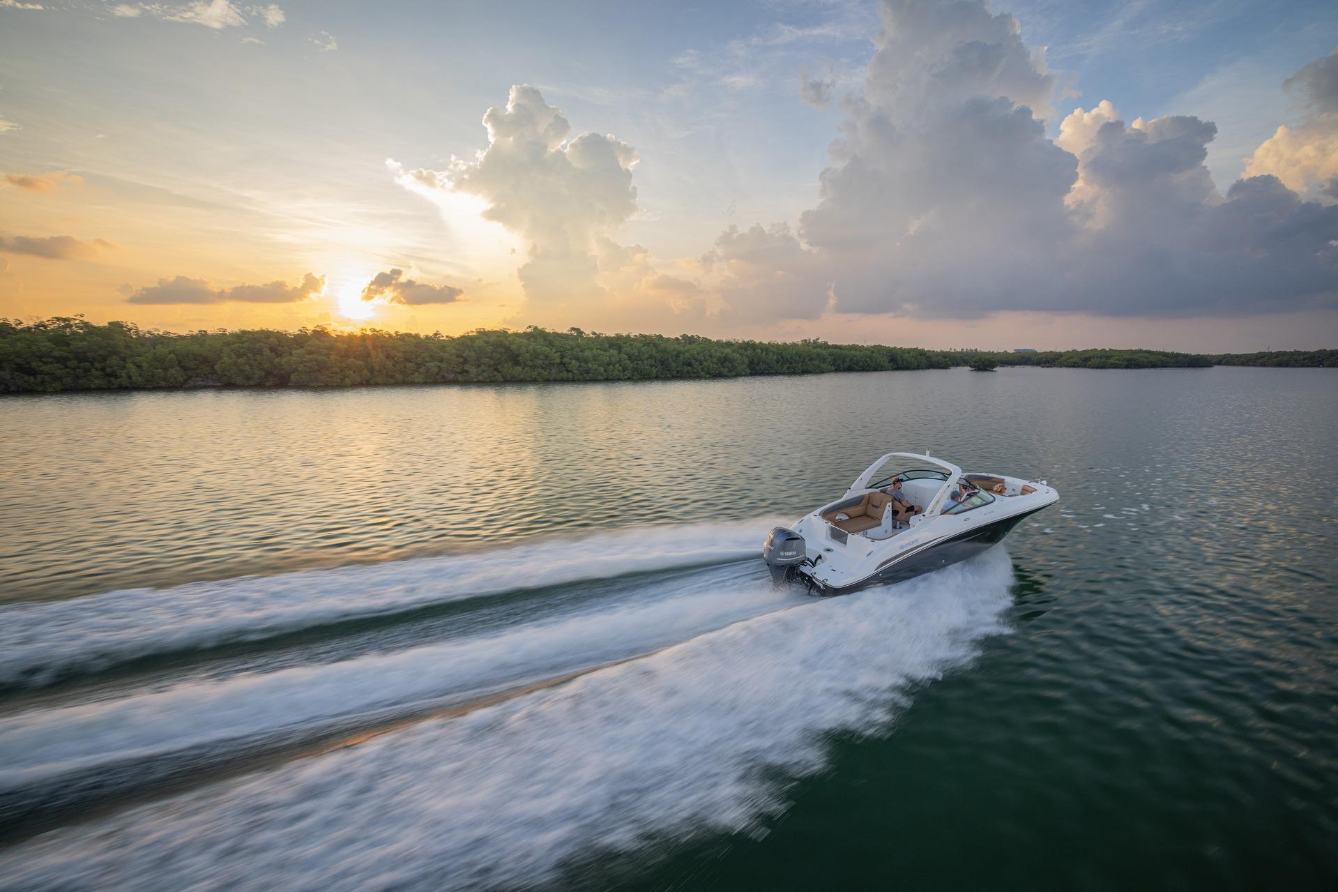 2026 Hurricane SunDeck 2690 OB cruising on serene water at sunset.