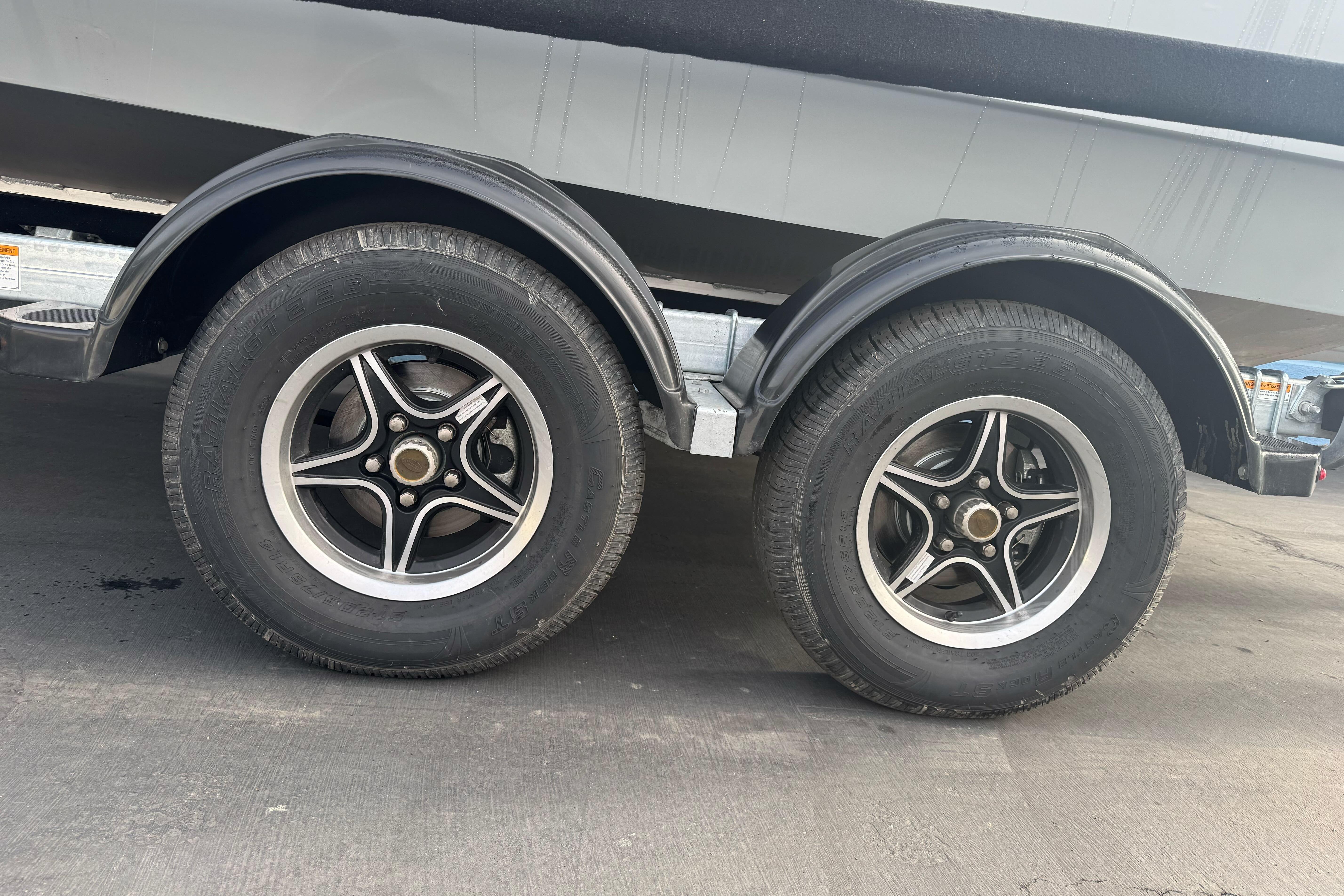 Trailer wheels of a 2026 KingFisher 2025 Escape boat on pavement.