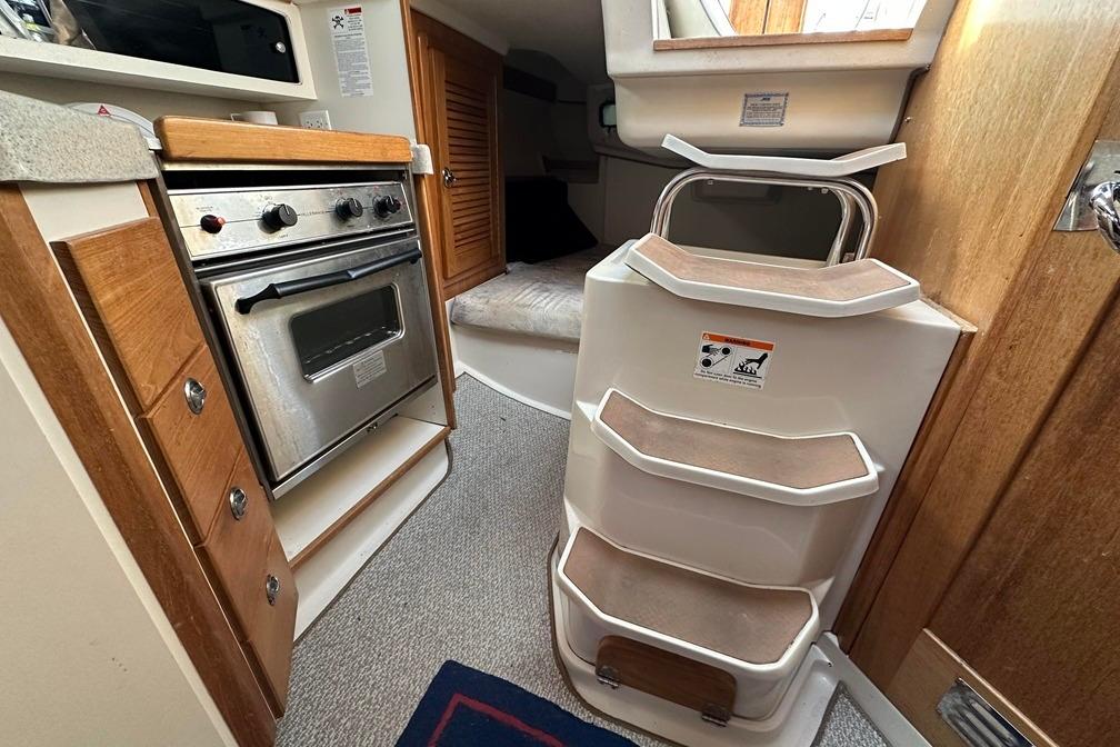 Interior of 2005 Catalina 28 MkII sailboat with compact kitchen and steps.
