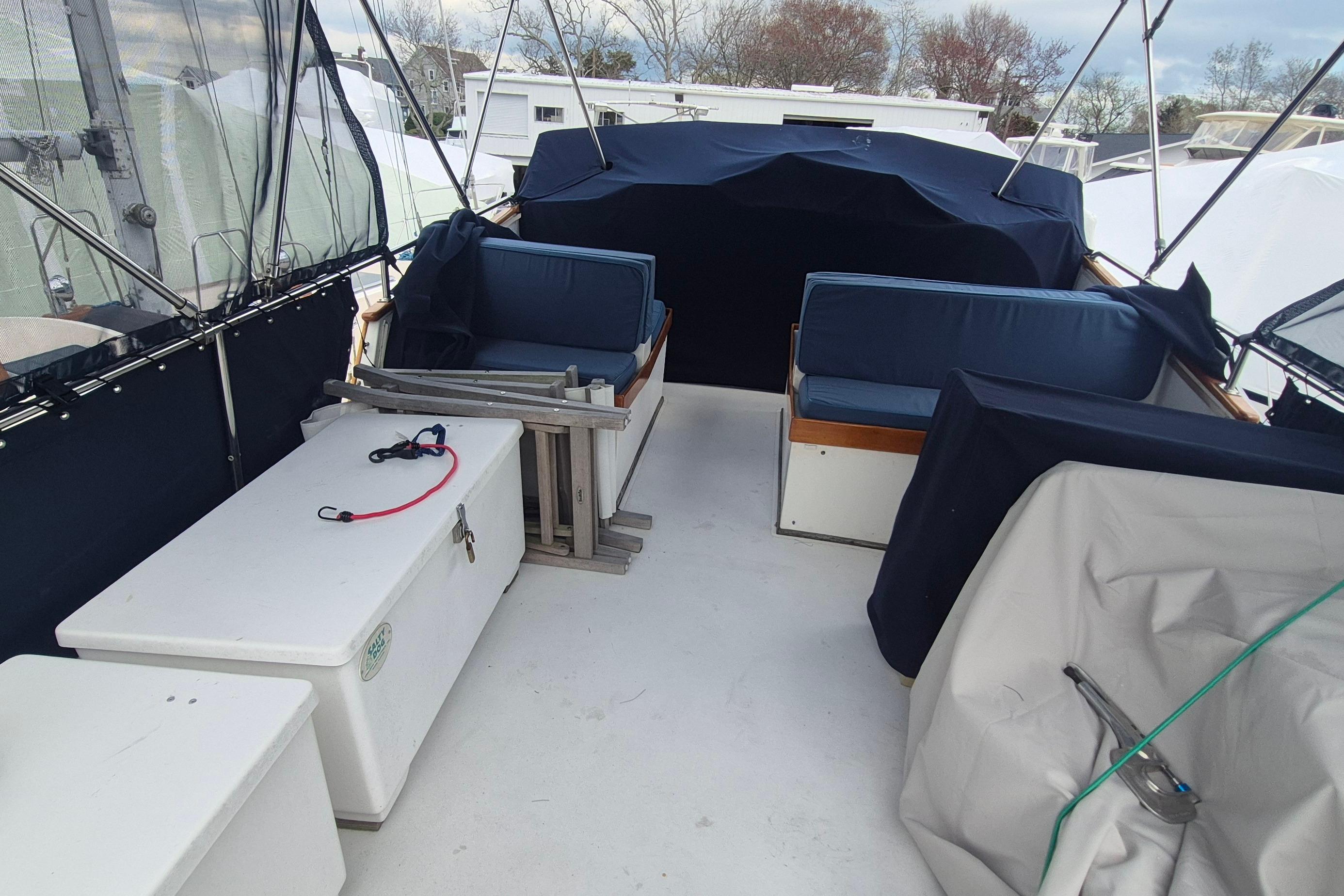 1983 Grand Banks 42 Motoryacht deck with seating and storage, covered in navy canvas.
