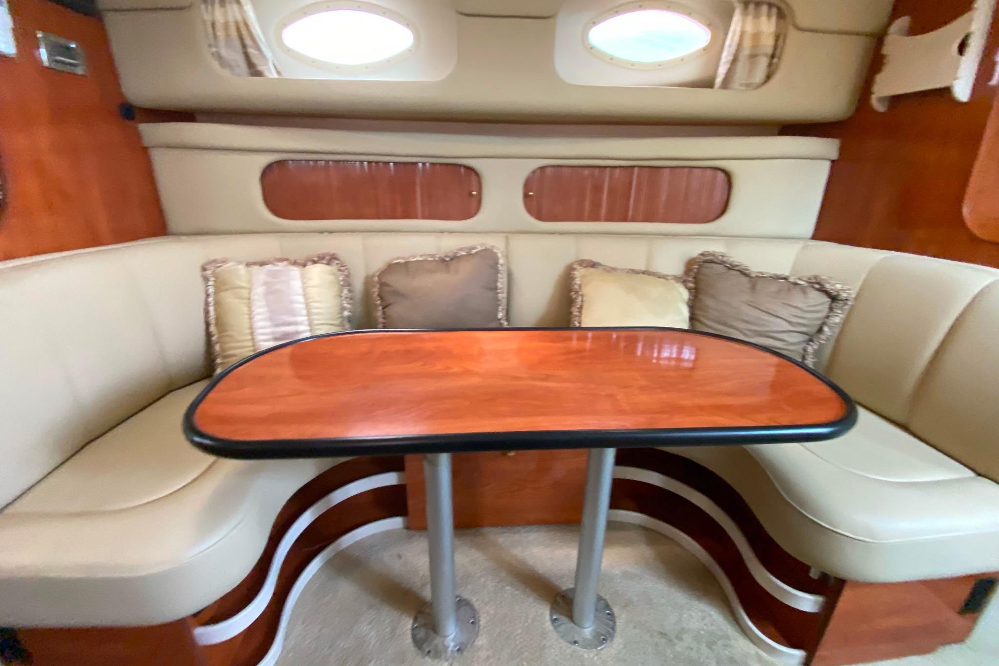 2003 Rinker Fiesta Vee 342 cabin interior with cushioned seating and wooden table.