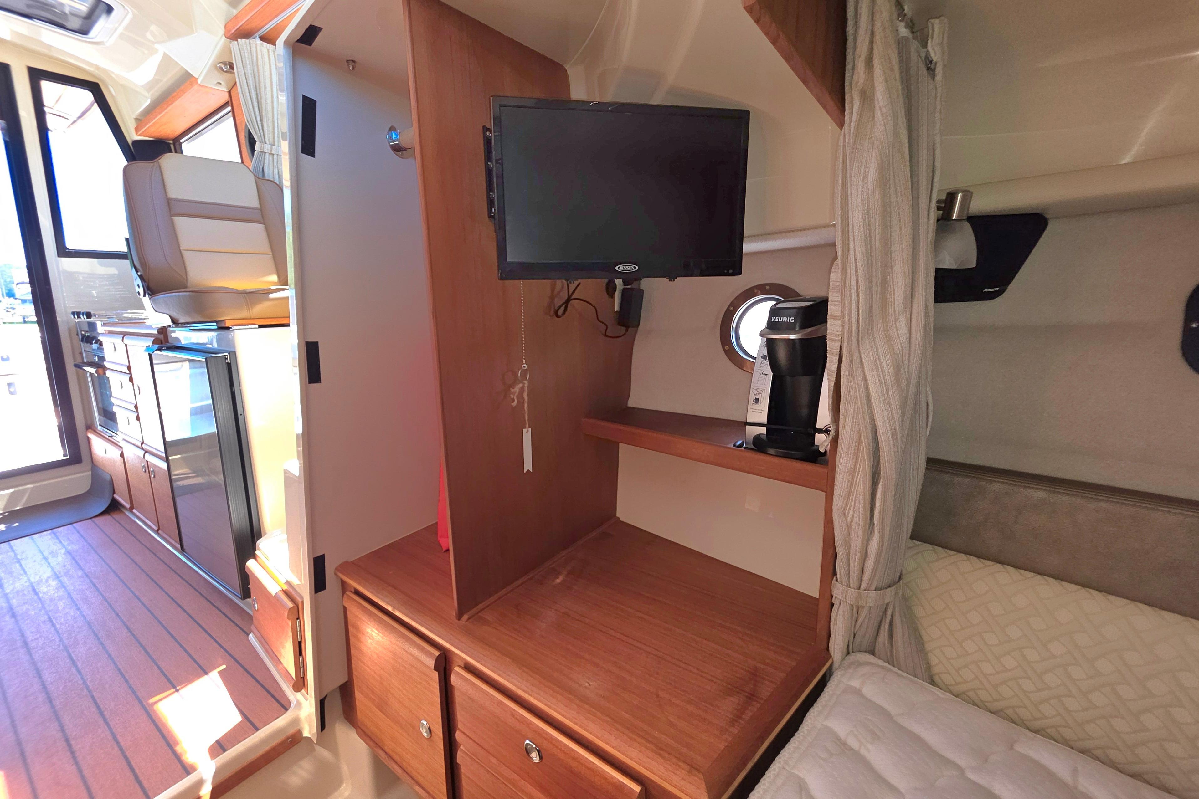 2021 Ranger Tug R27 interior with TV, coffee maker, and wooden cabinetry.