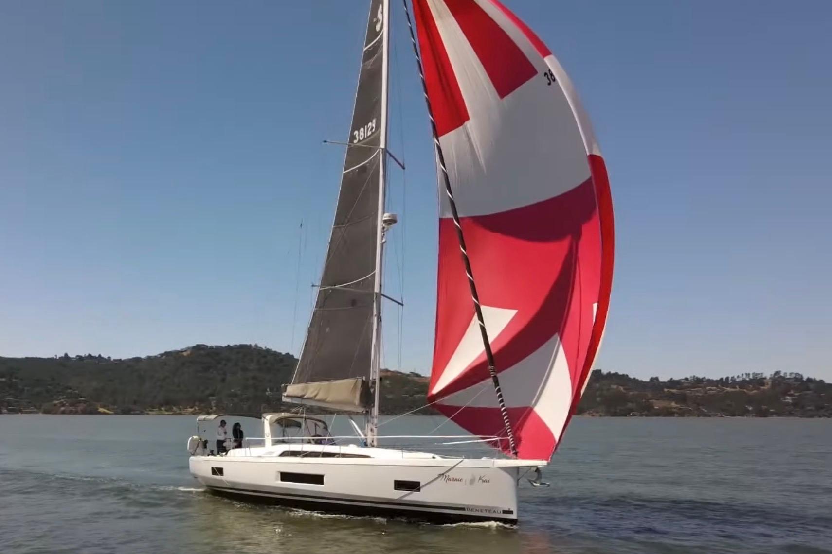 2020 Beneteau Oceanis 46.1 sailing with vibrant red and white spinnaker on a sunny day.