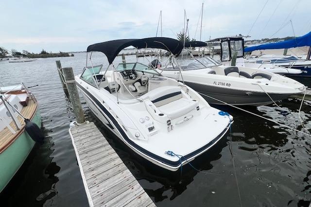 2011 Chaparral 224 Sunesta boat docked at marina, featuring sleek design and canopy.
