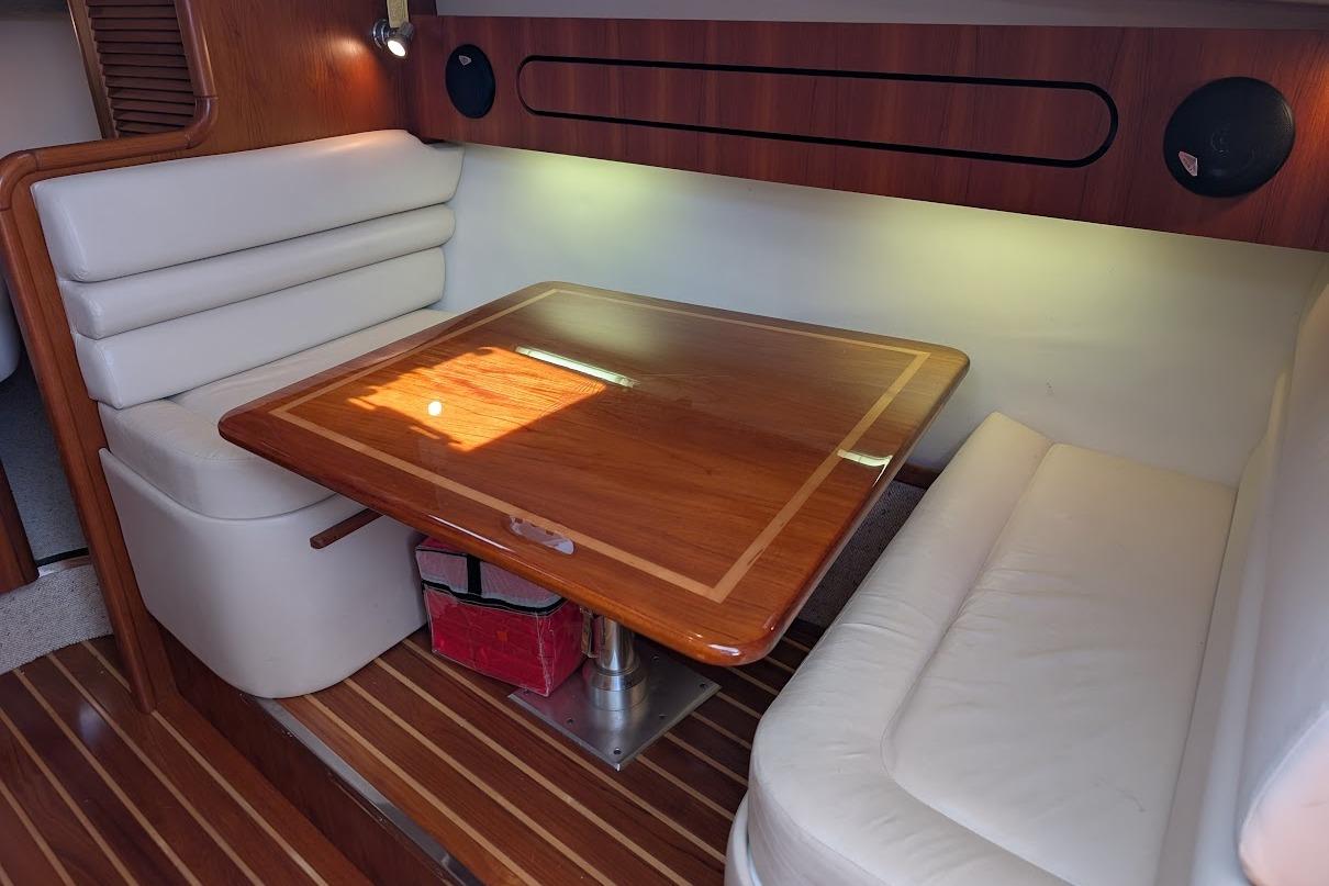 Luxurious cabin interior of 2000 Pursuit 3400 Express with wooden table and cushioned seating.